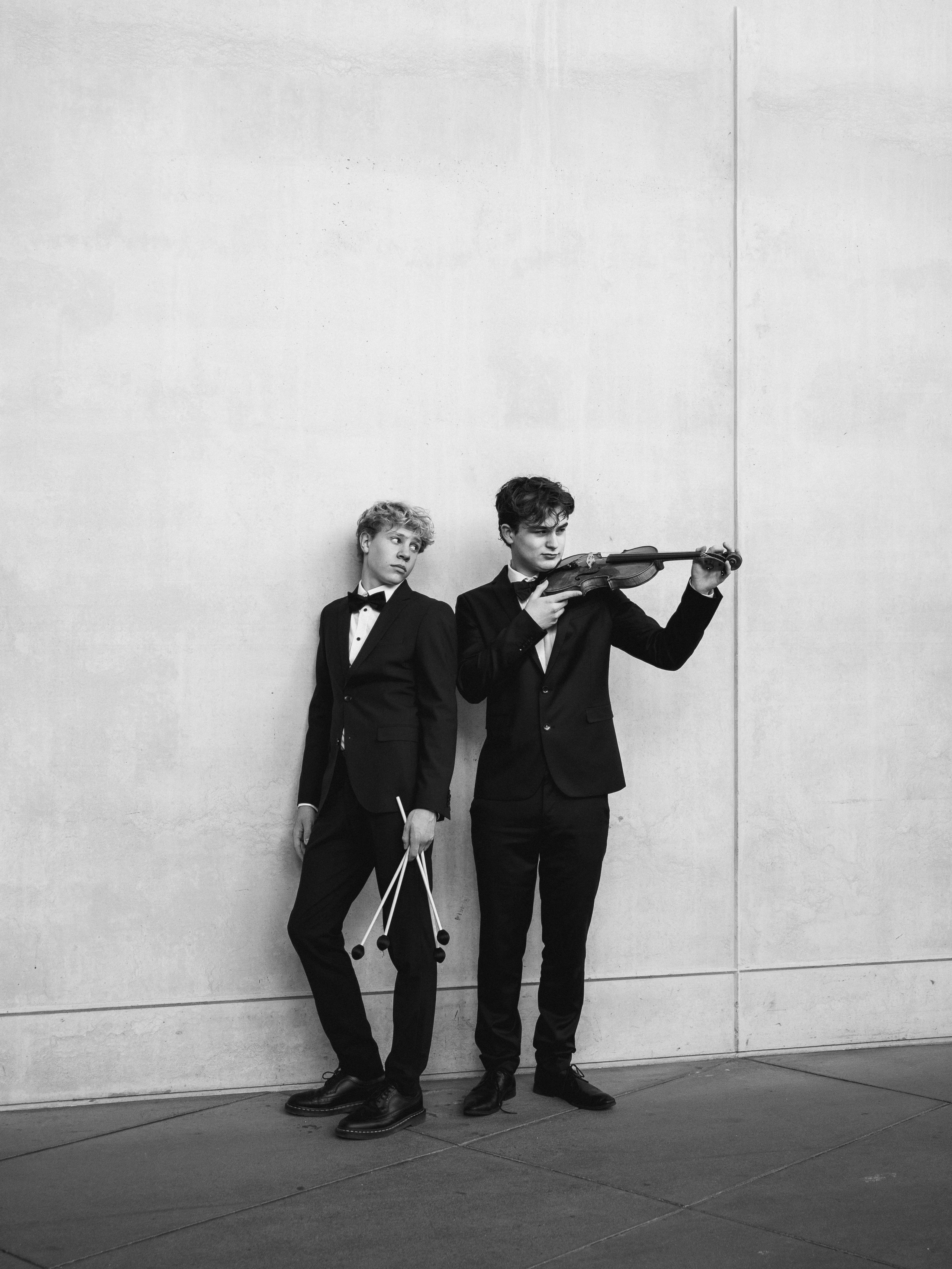 Two young men in suits with musical instruments