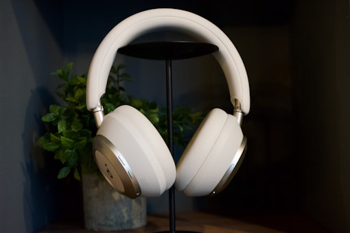White headphones on a stand with plant.