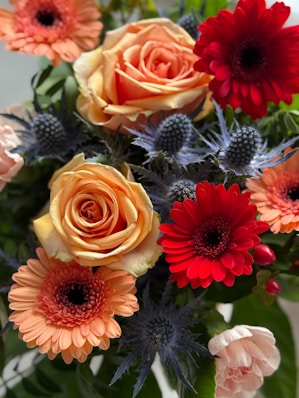 A vibrant bouquet of roses, gerbera daisies, and thistles.