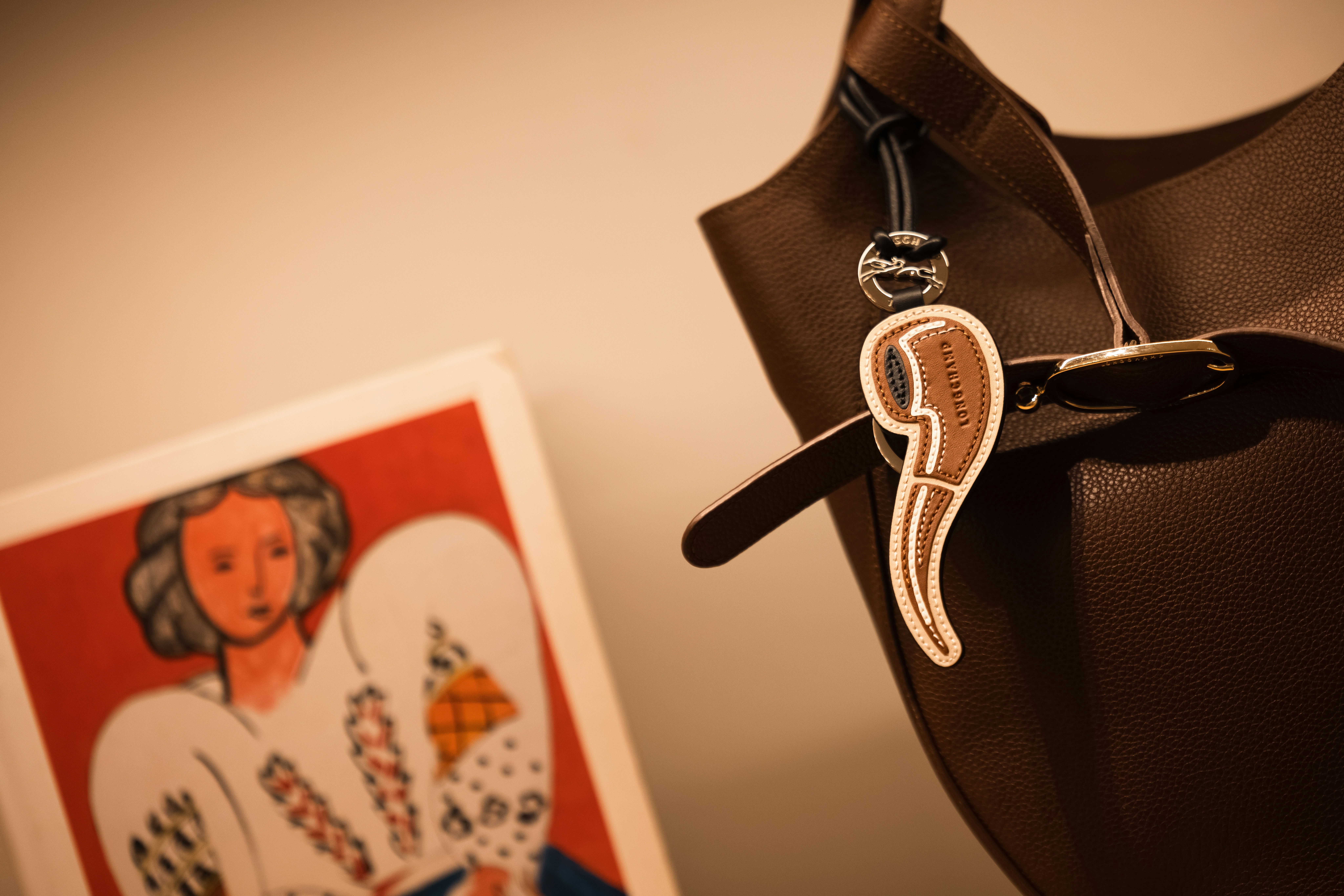 Brown handbag with a comma-shaped charm