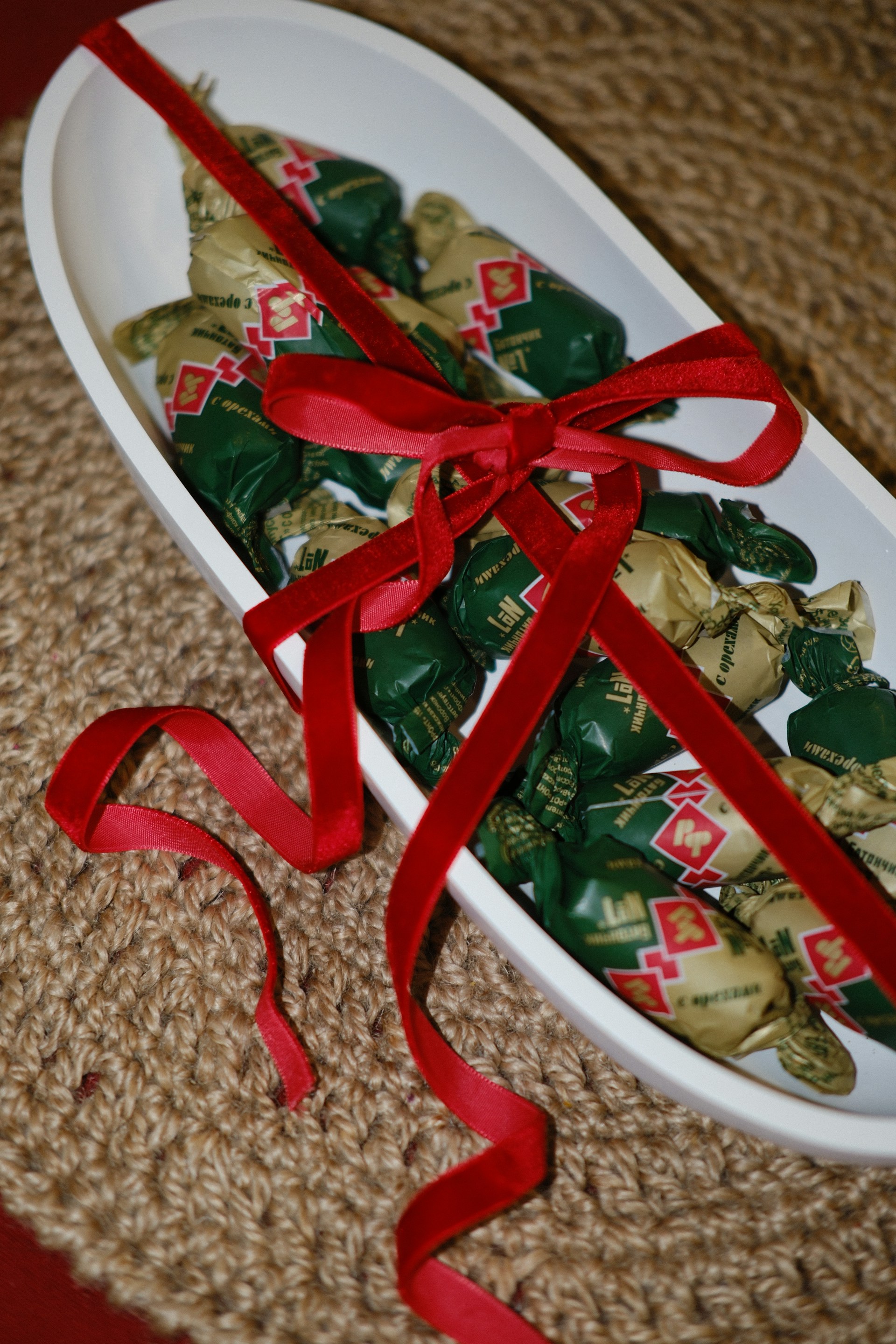 Wrapped candies in a white dish with red ribbon.