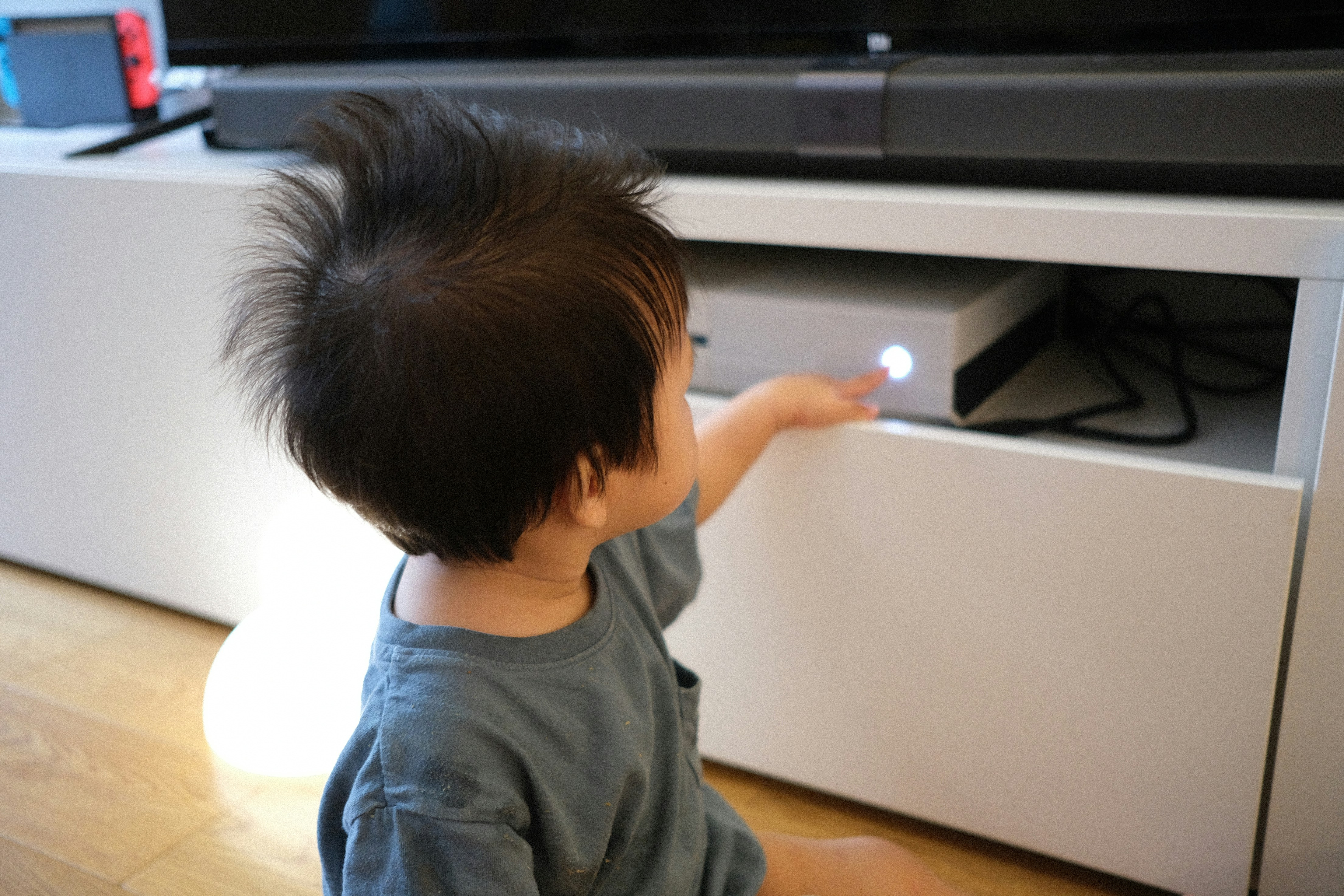 Young child reaching for a gaming console.