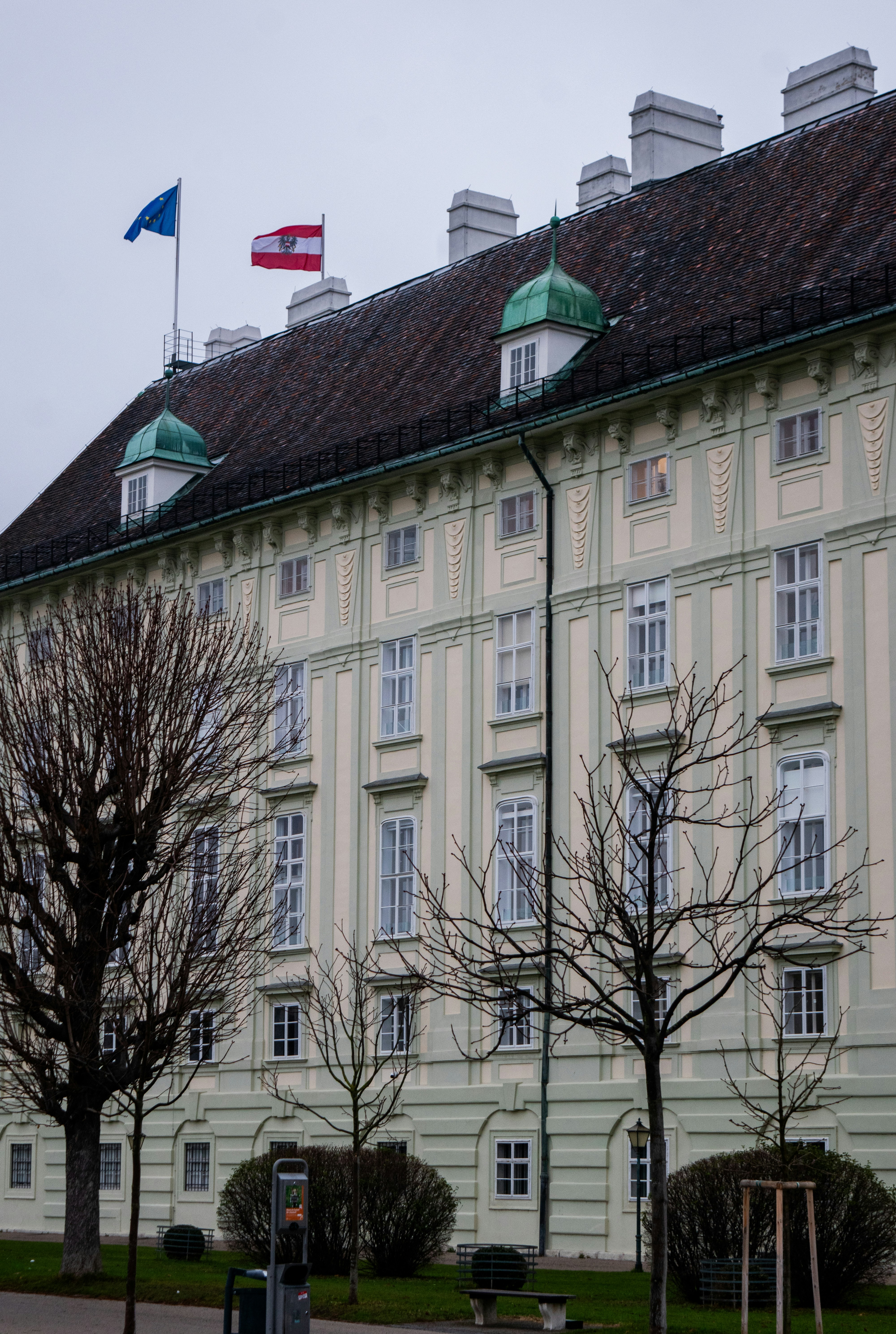 A grand building with flags flying on a cloudy day.