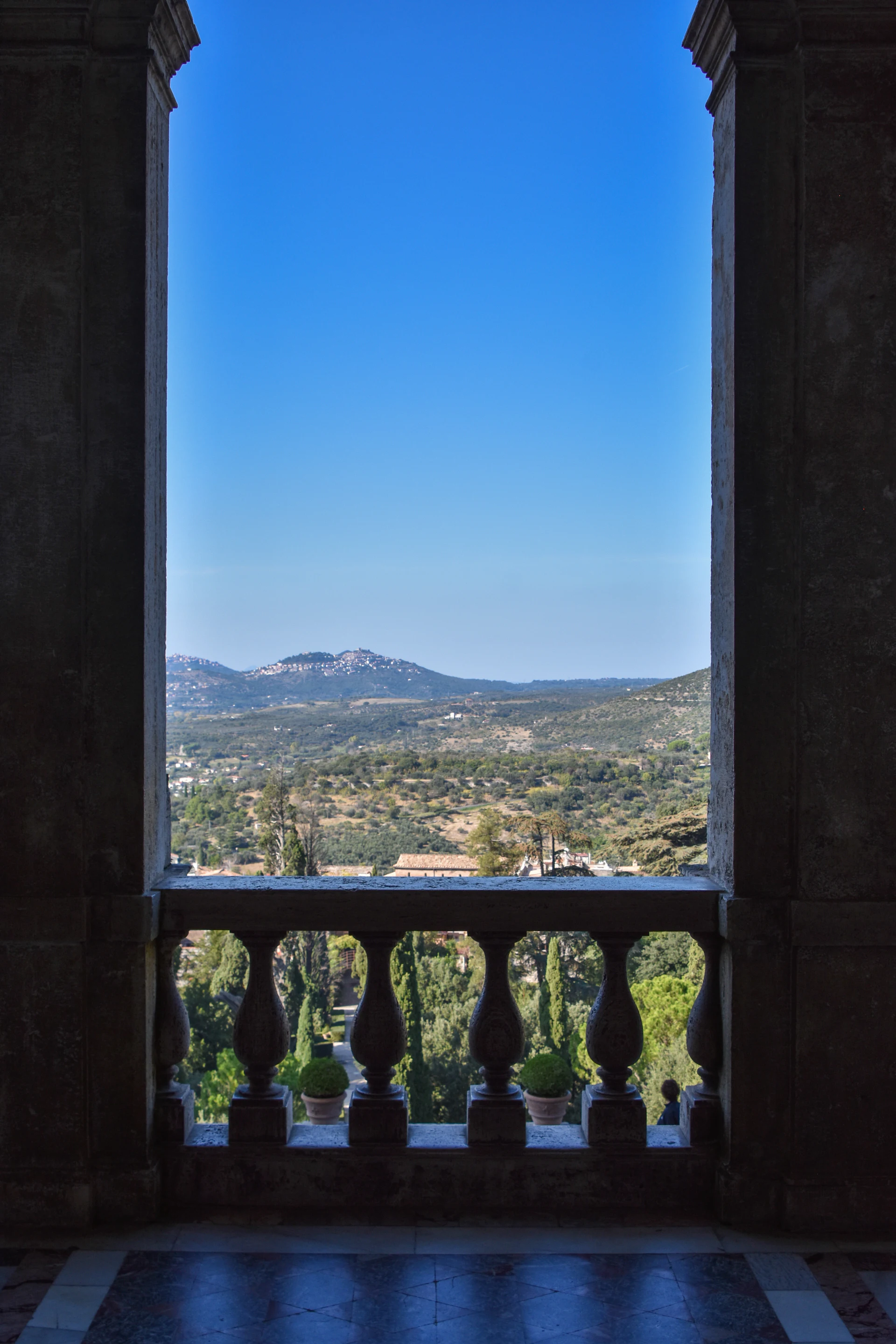 Stone balustraded estate terrace framing formal gardens and distant hills