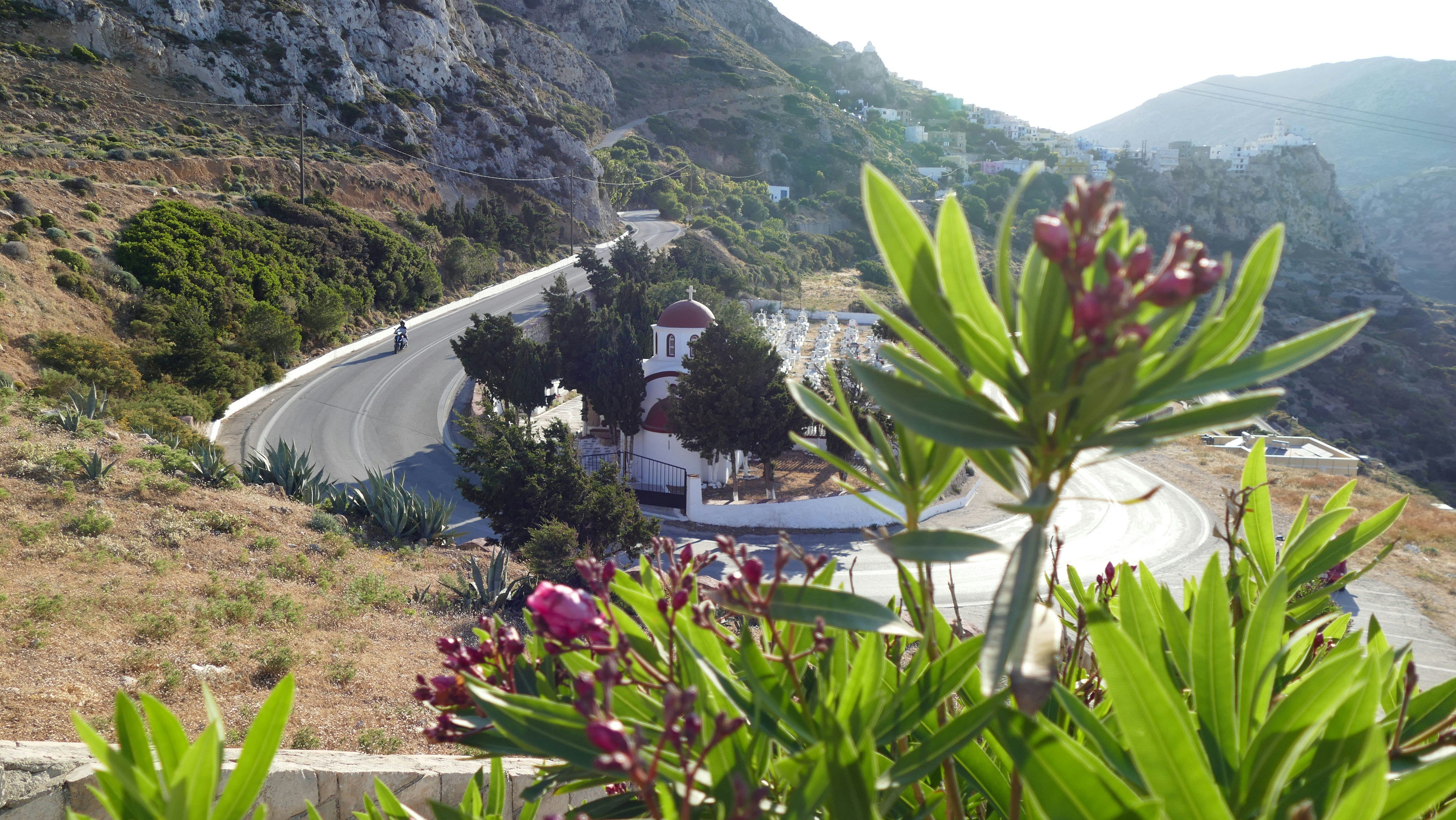 Winding mountain road with a small white building.