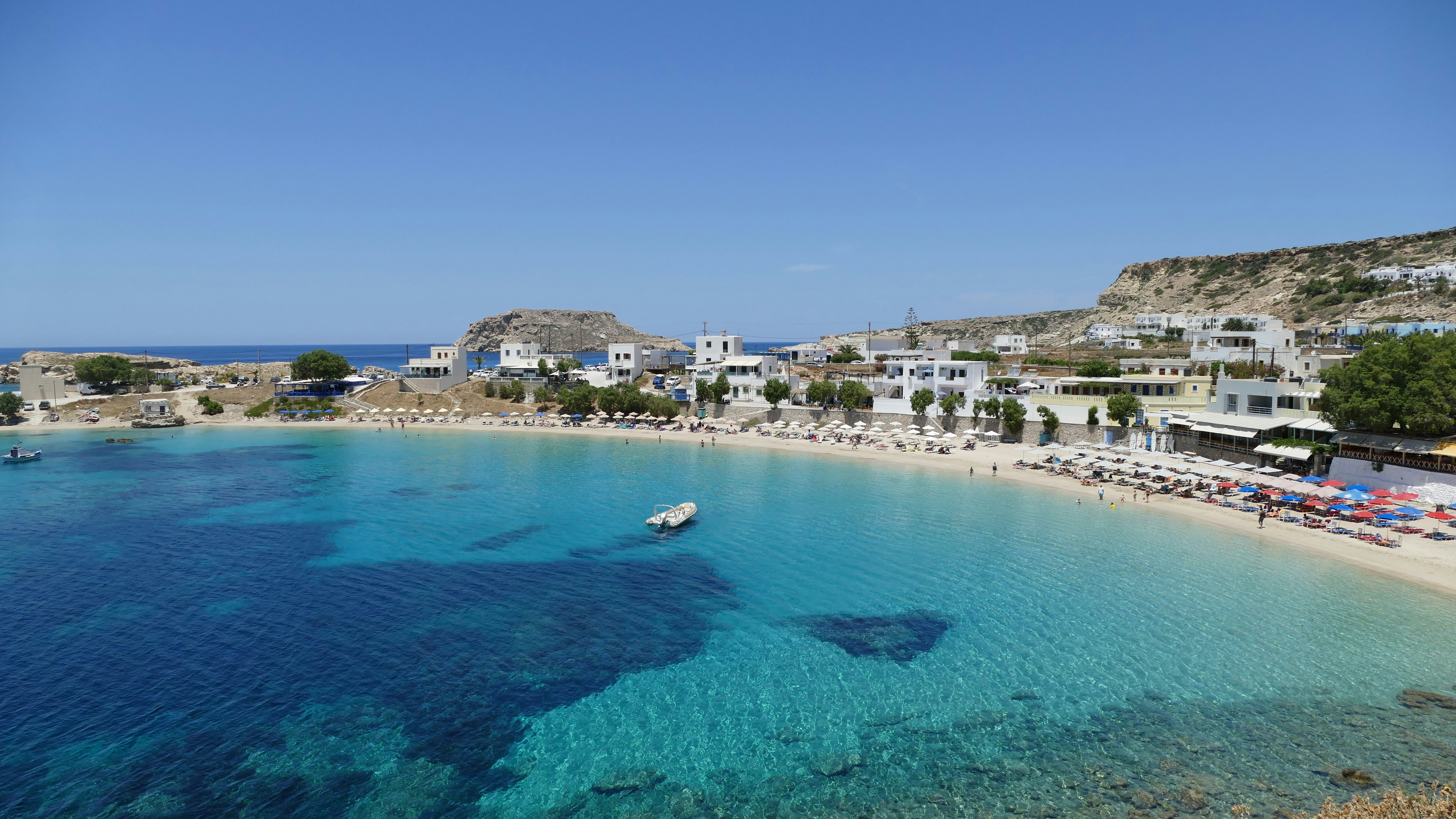 Beautiful beach with clear turquoise water and white buildings.
