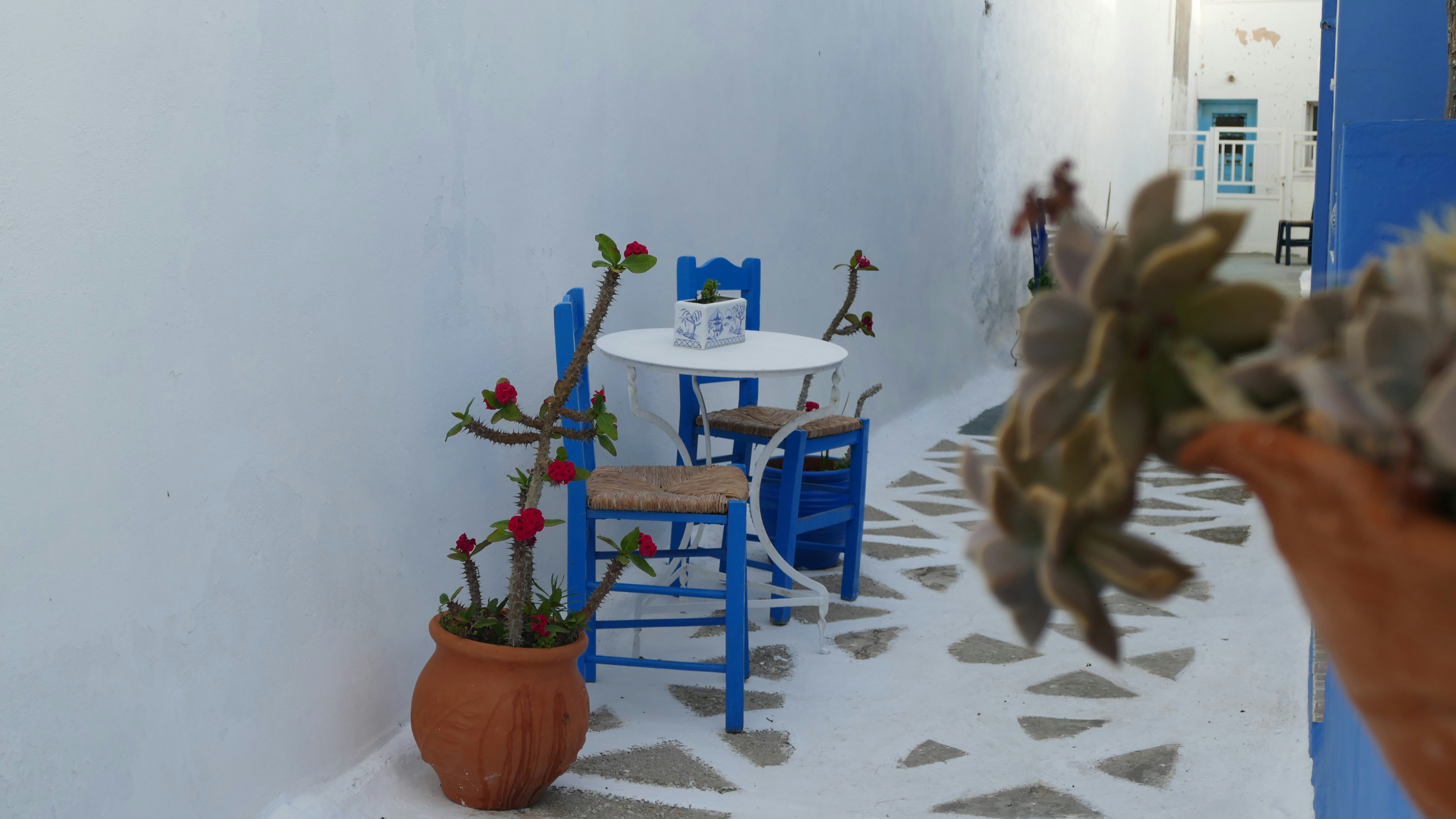 Small outdoor cafe table with blue chairs in greece