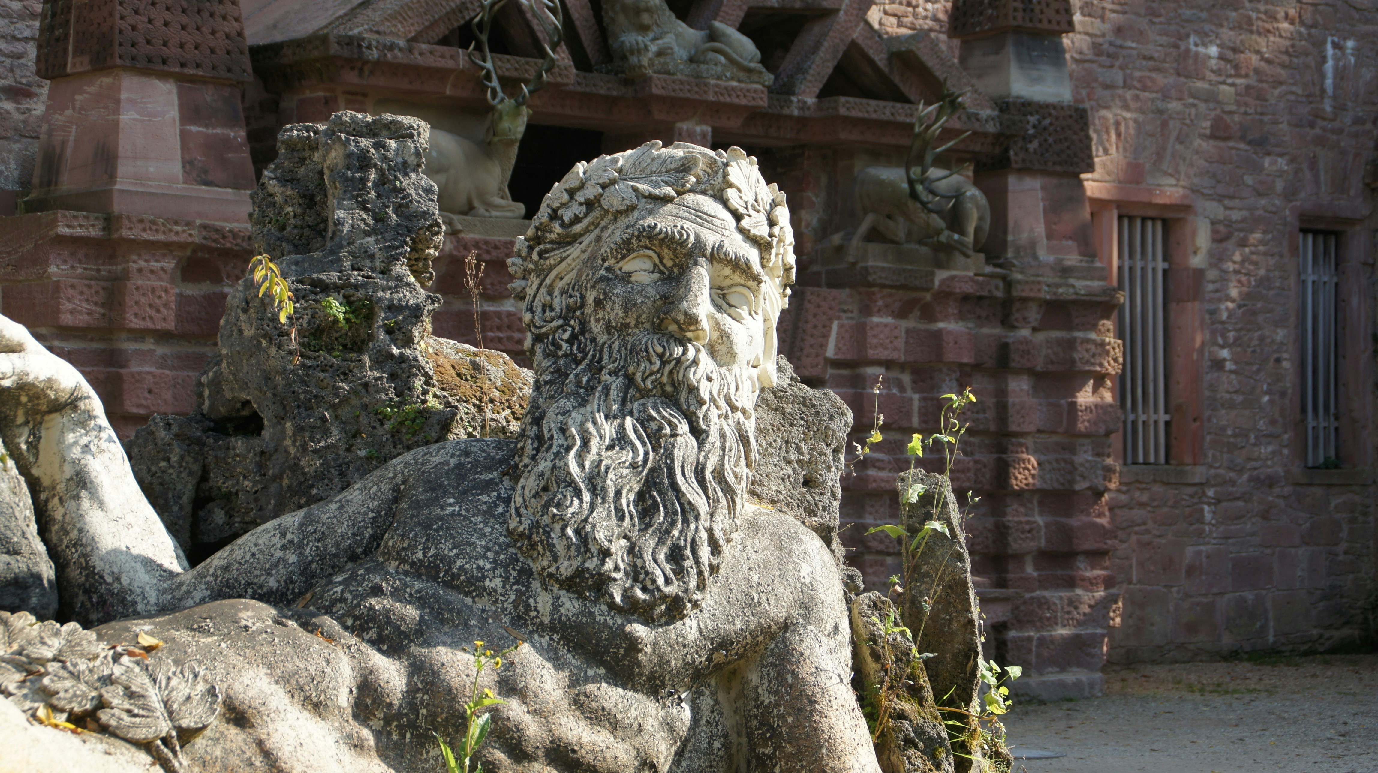 Steinskulptur eines bärtigen Mannes mit einem Kranz.