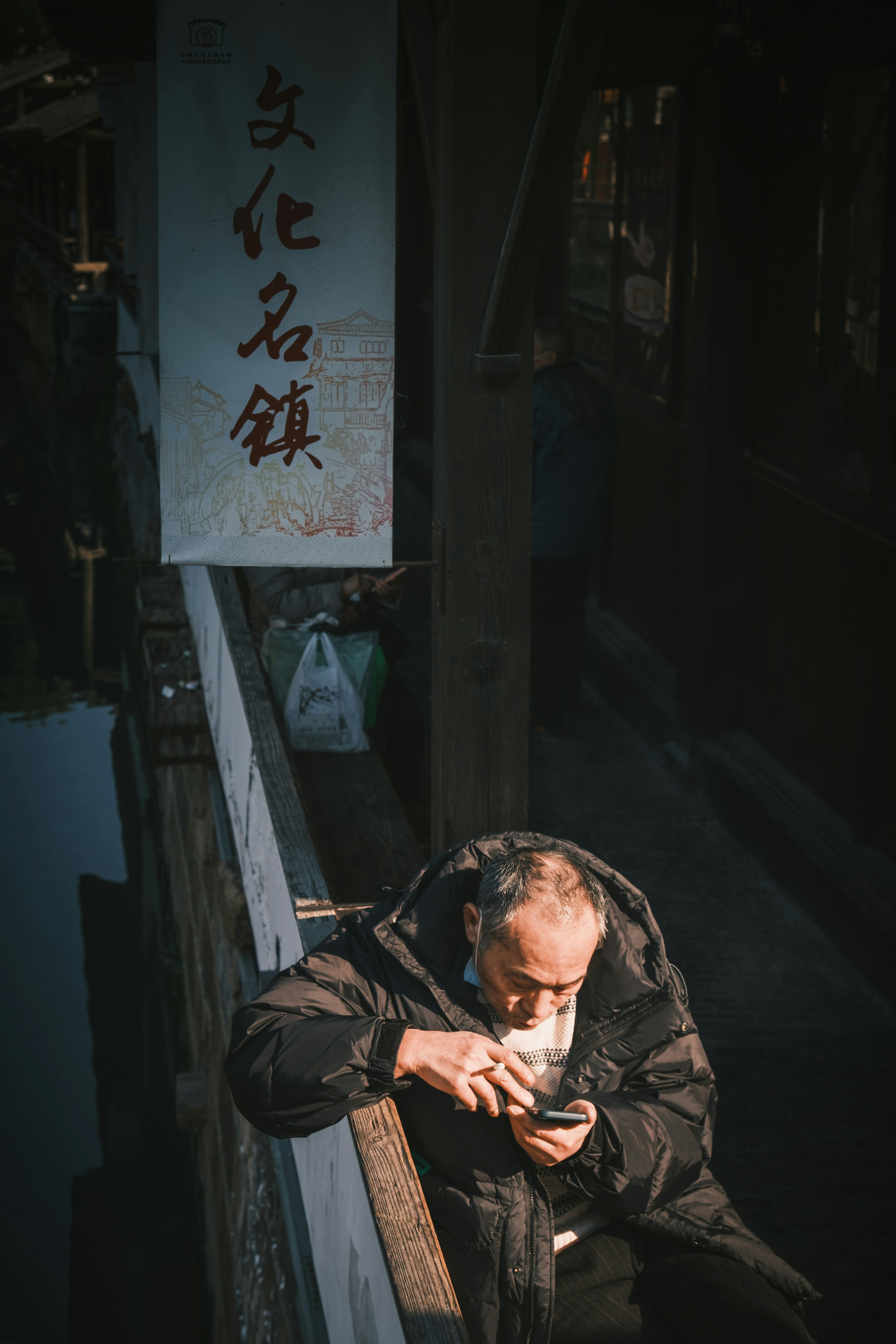 Älterer Mann auf einer Brücke schaut auf sein Handy