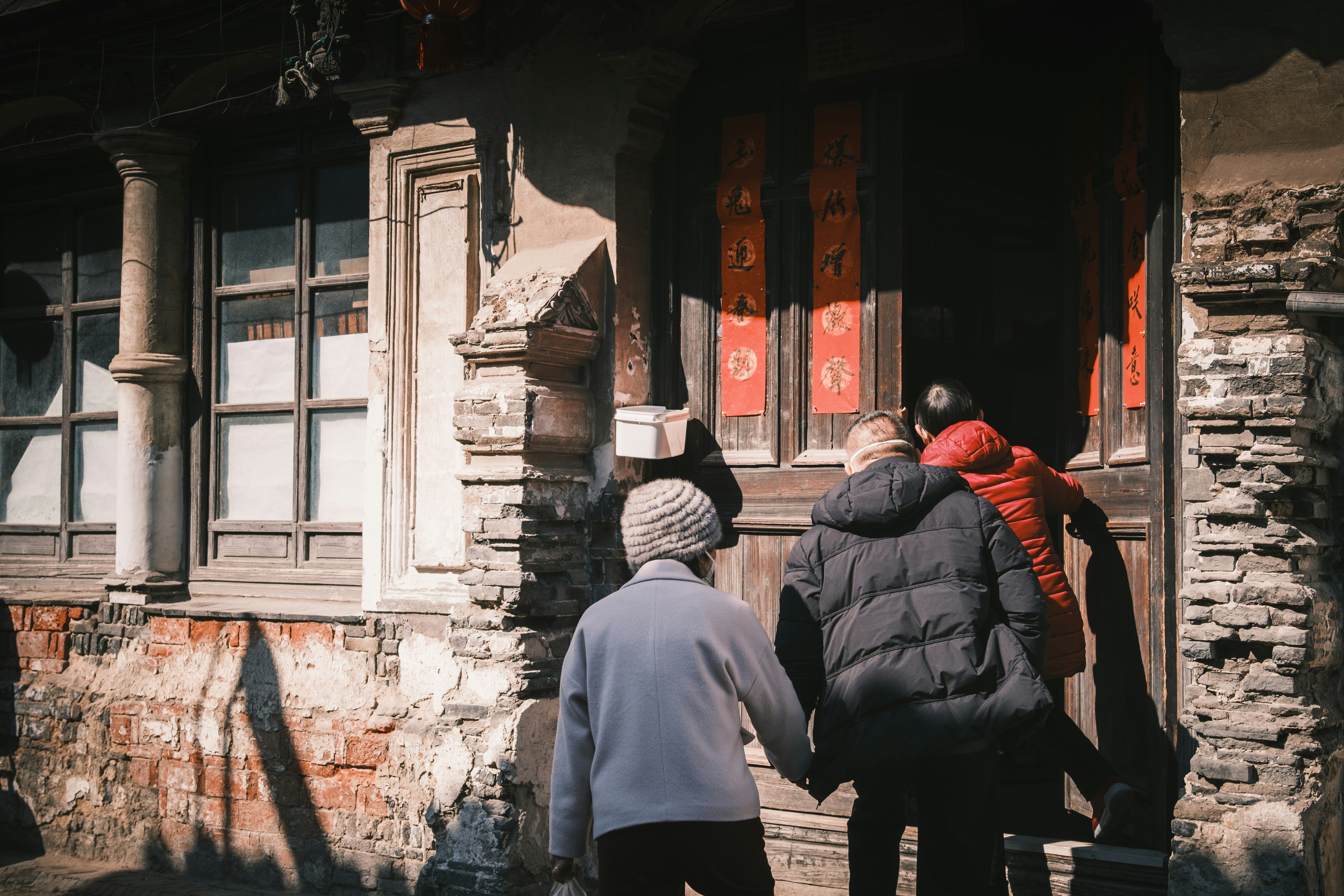 People entering an old building with ornate doors.