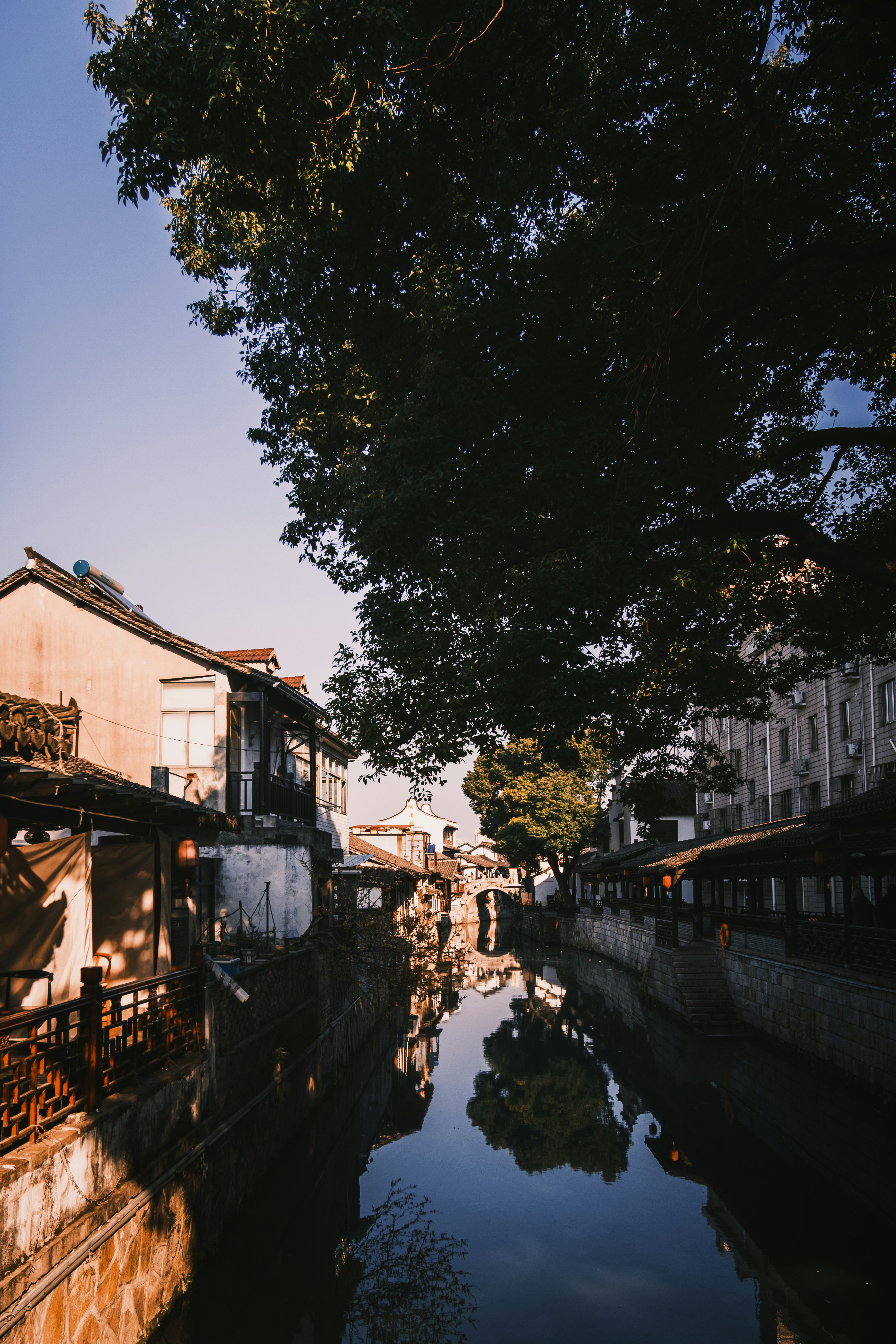 Canal reflecting buildings and trees under clear sky