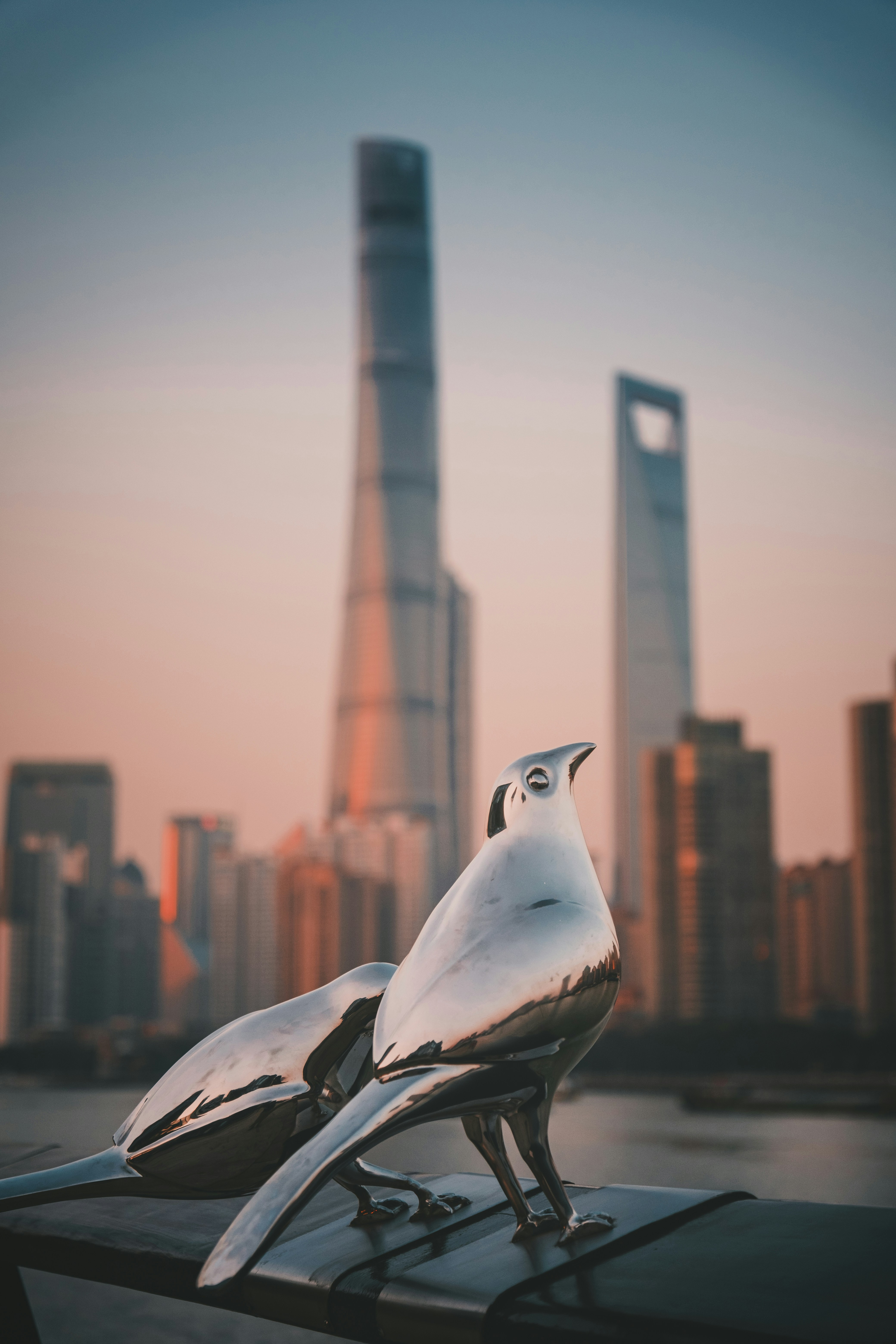 Two metal bird sculptures with city skyline background.
