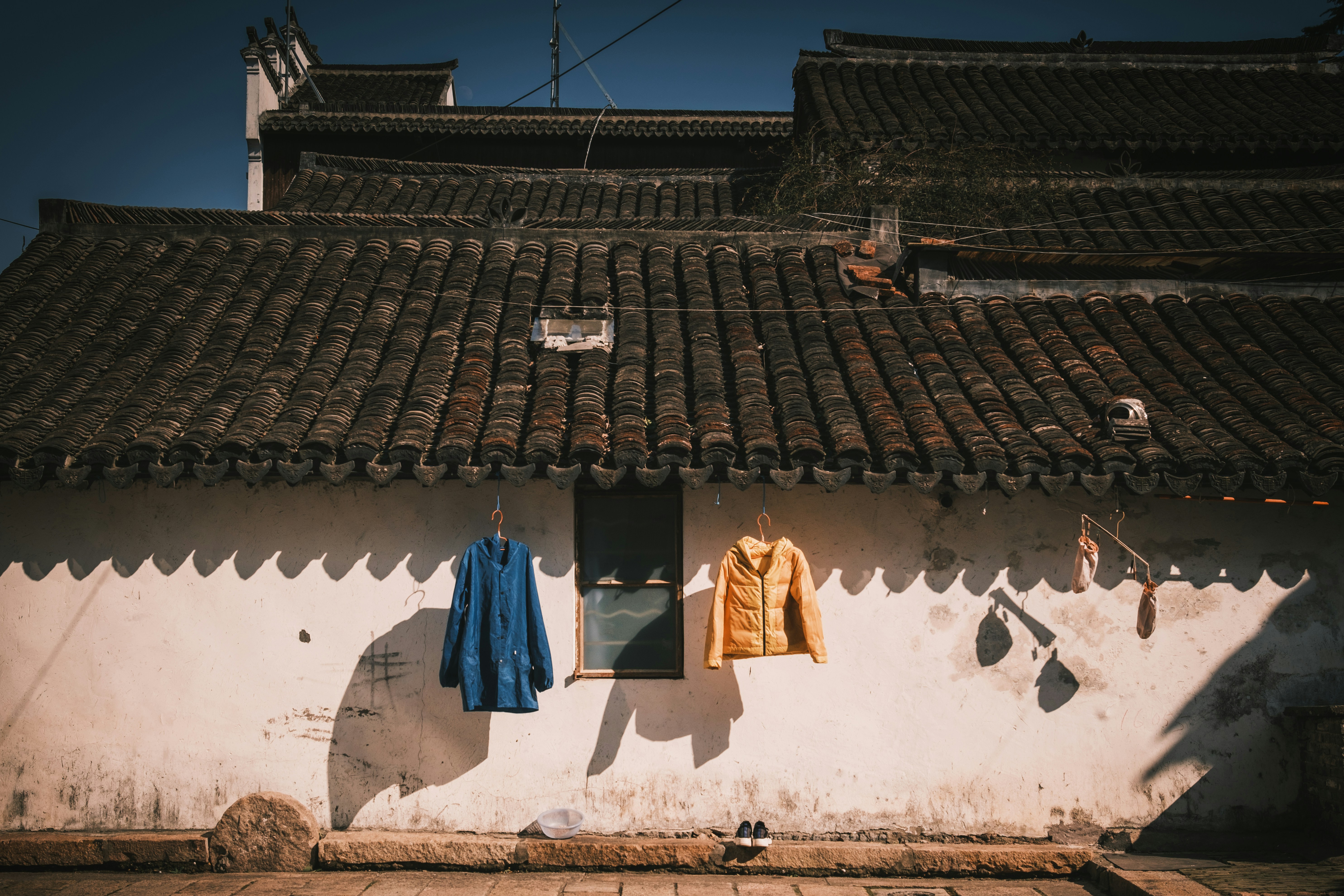 Two jackets hanging on a white wall.