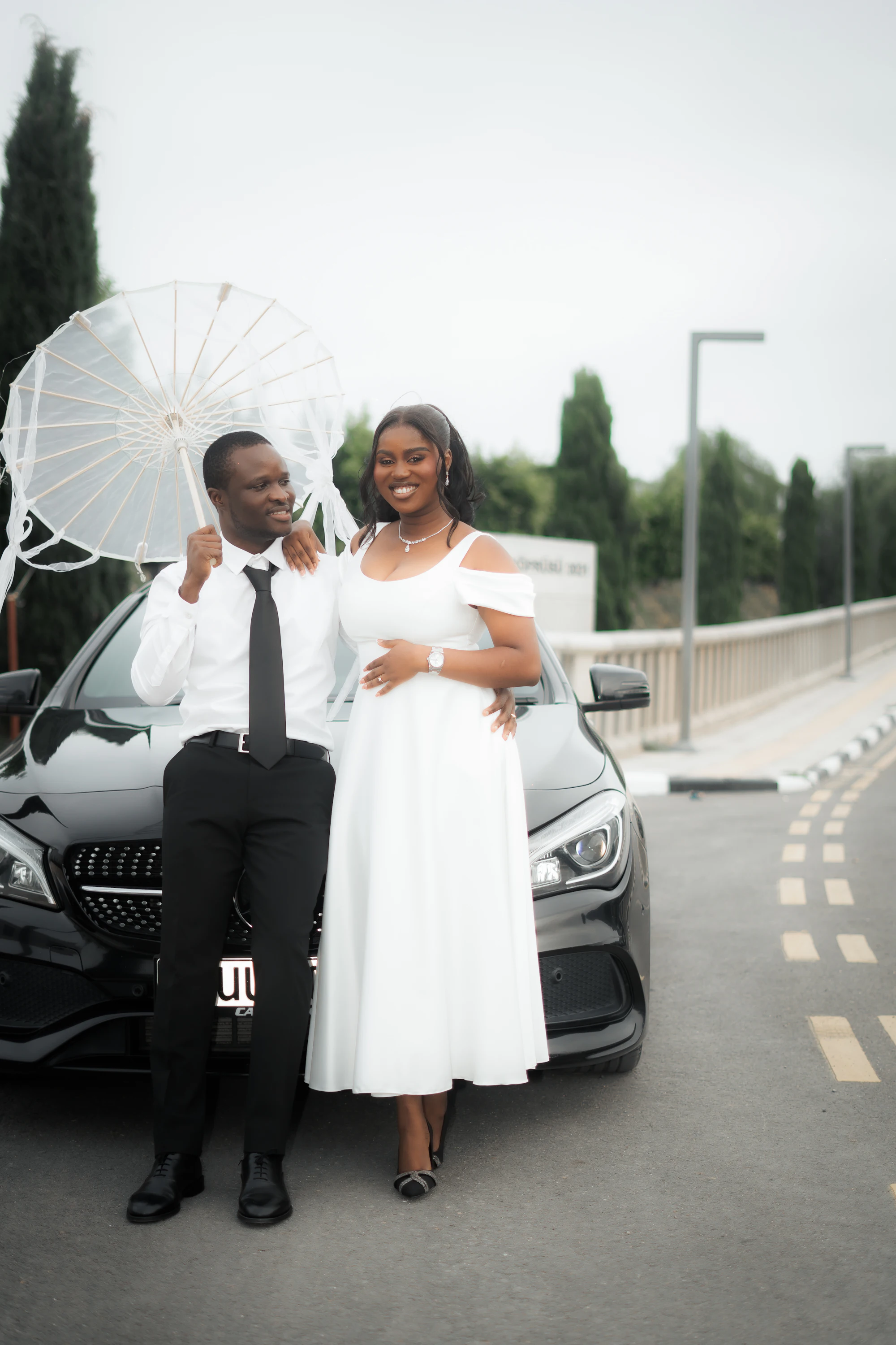 Couple de mariés devant une voiture noire de prestige avec chauffeur