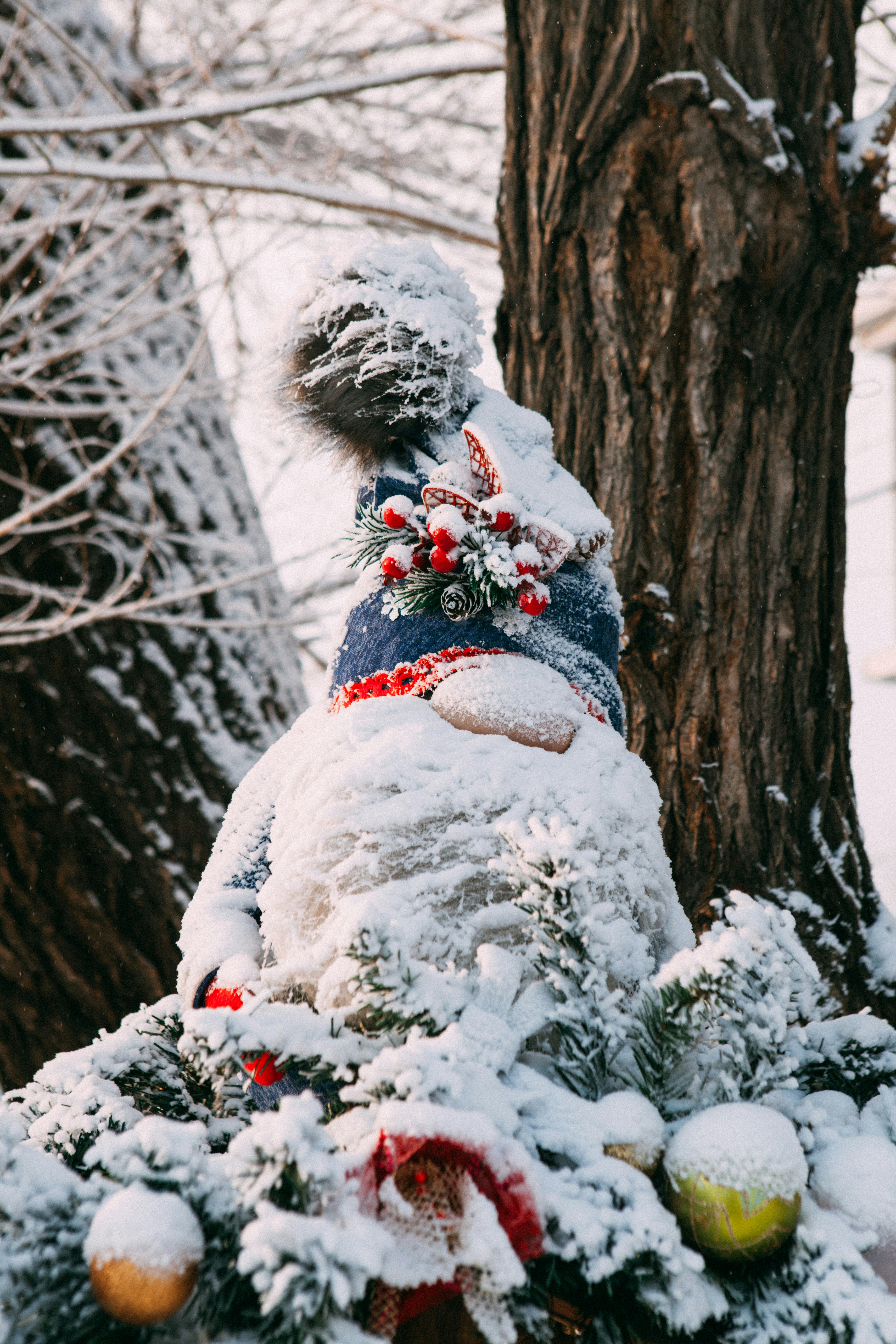 Snow-covered snowman decoration with festive ornaments.