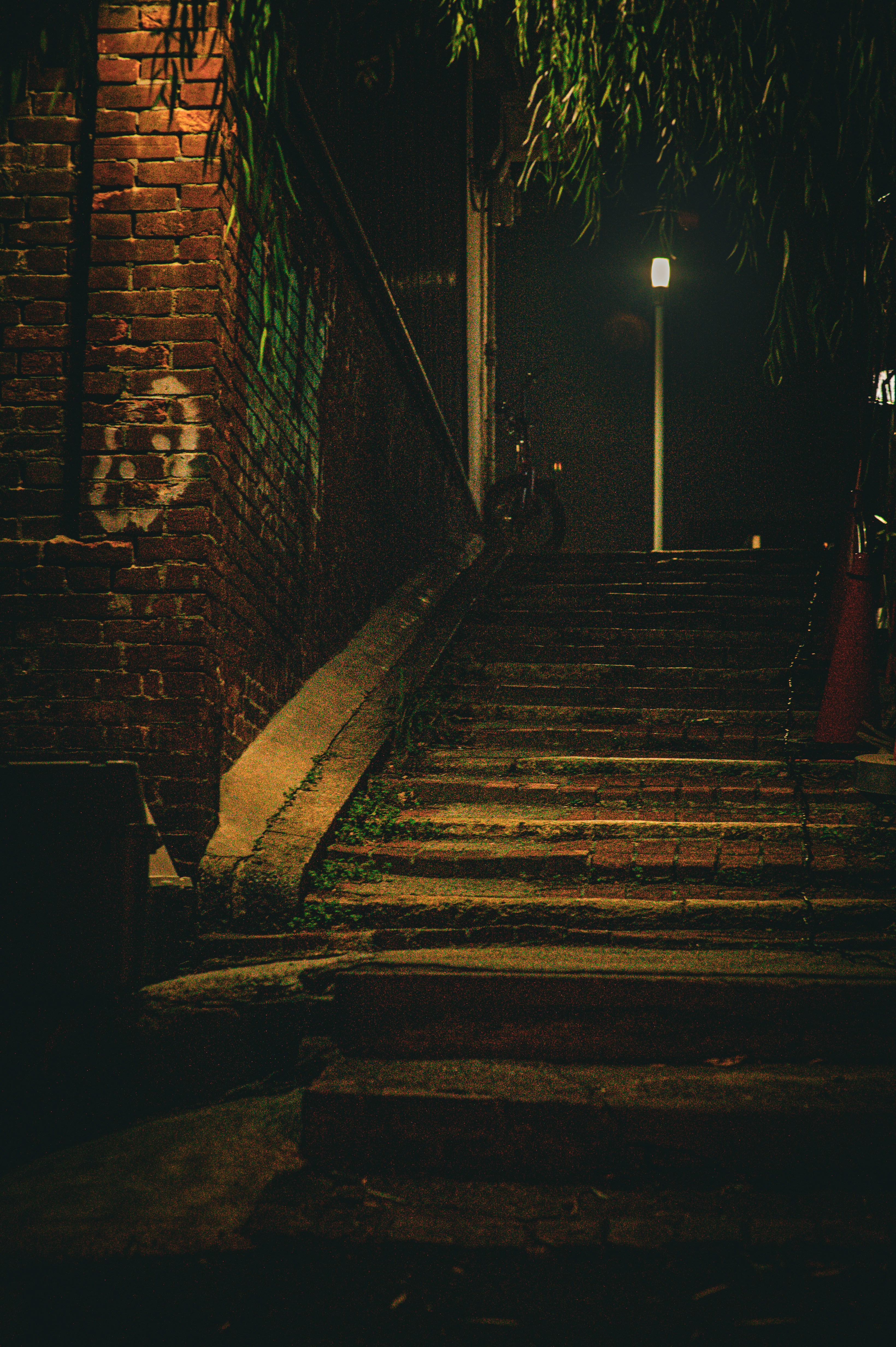 Dark brick staircase with a street lamp at night.