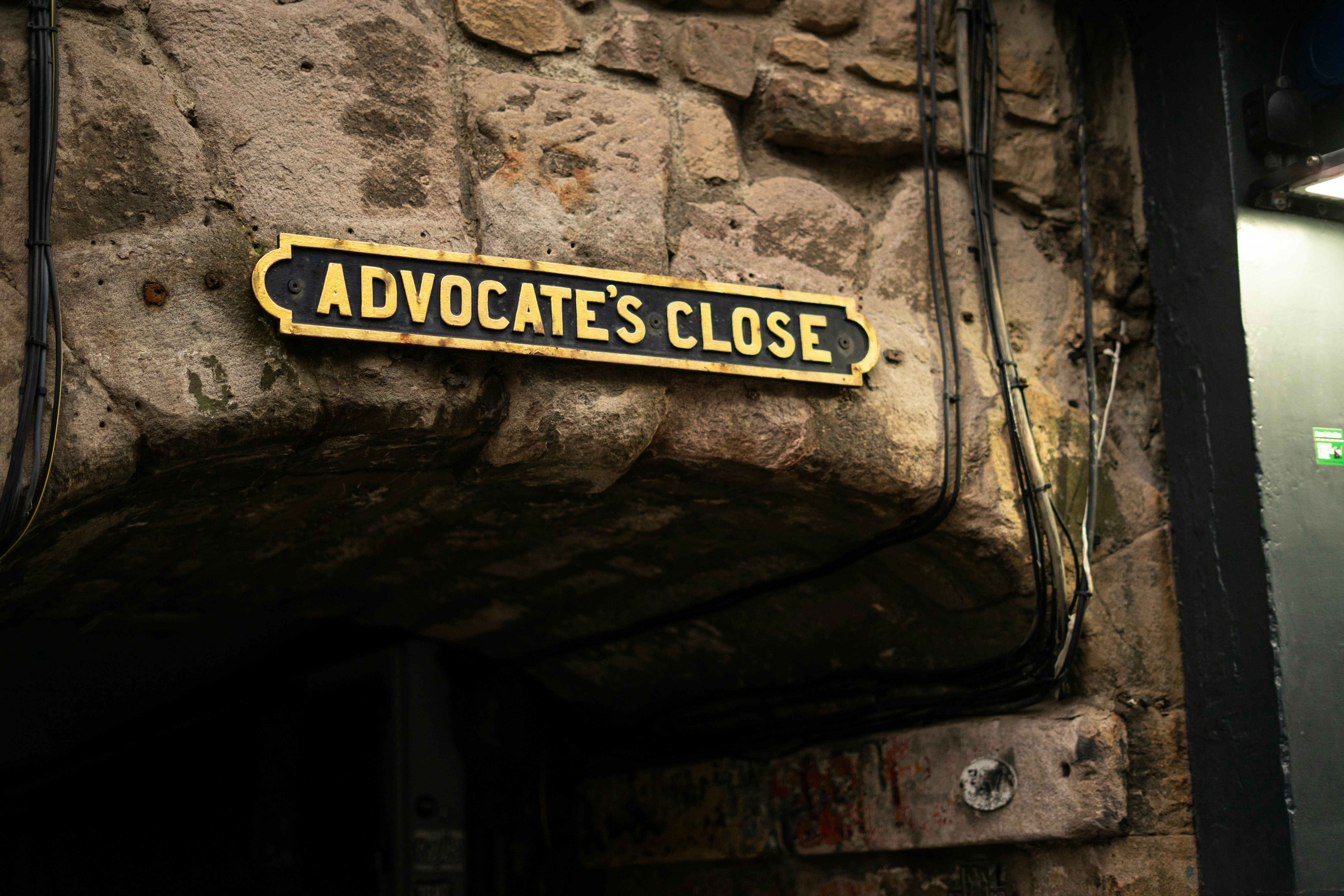 Advocate's close street sign on stone wall.