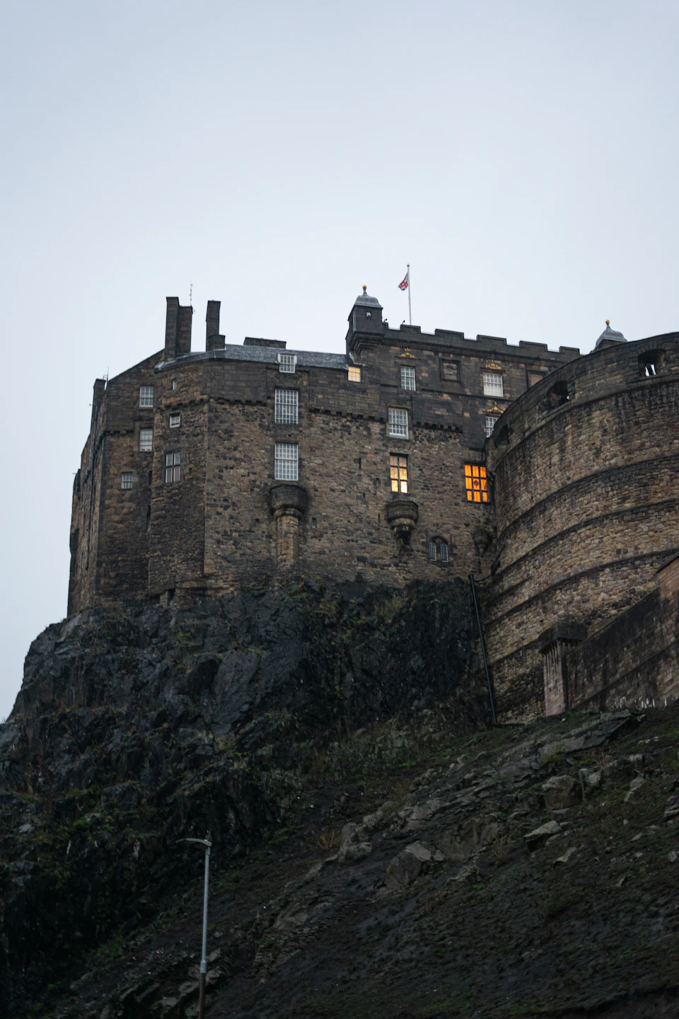 Castle perched on rocky cliff with stone walls and towers reaching towards the sky