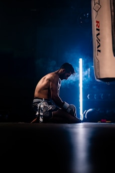 Boxer kneeling on floor with punching bag