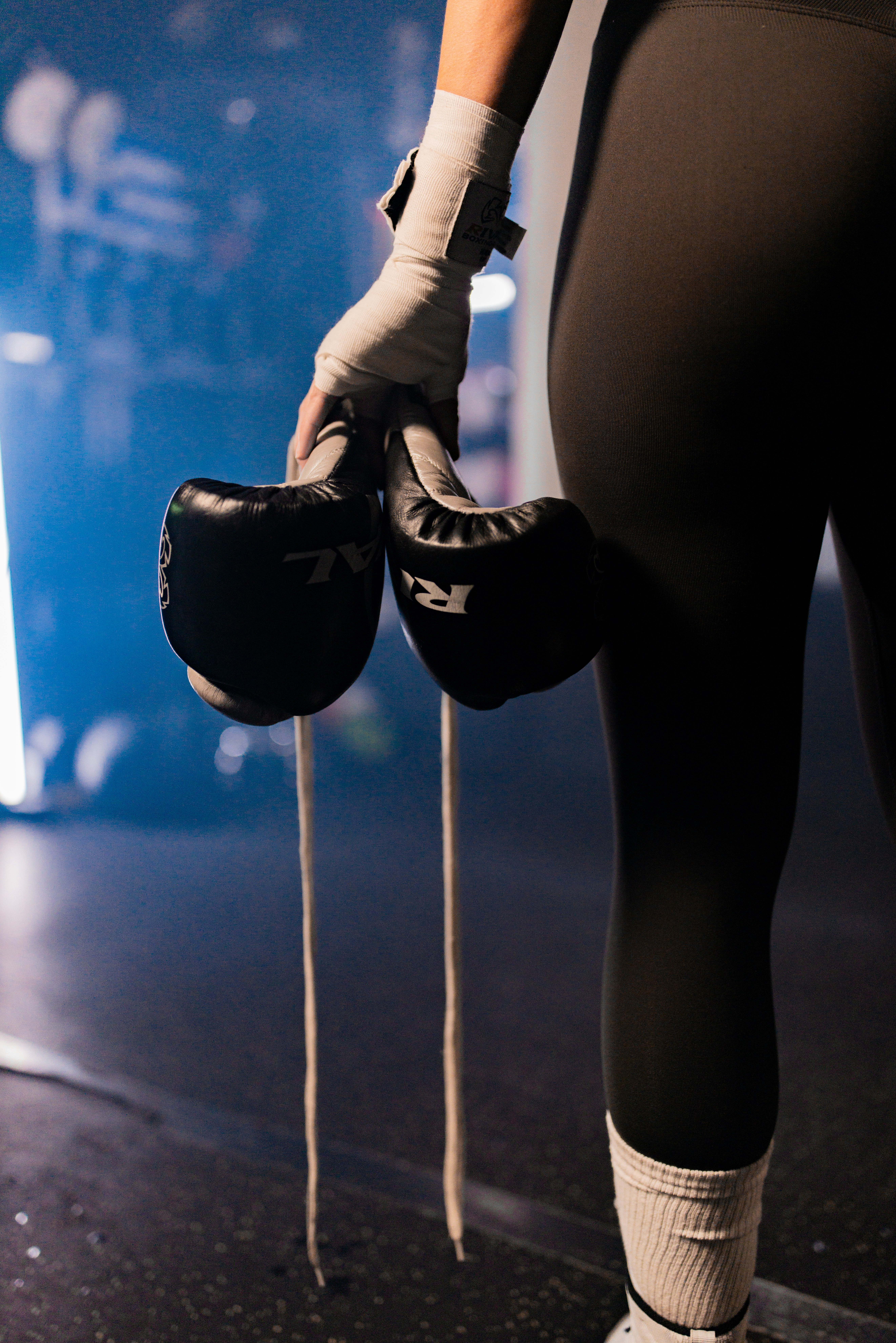 Person holding boxing gloves in a gym.