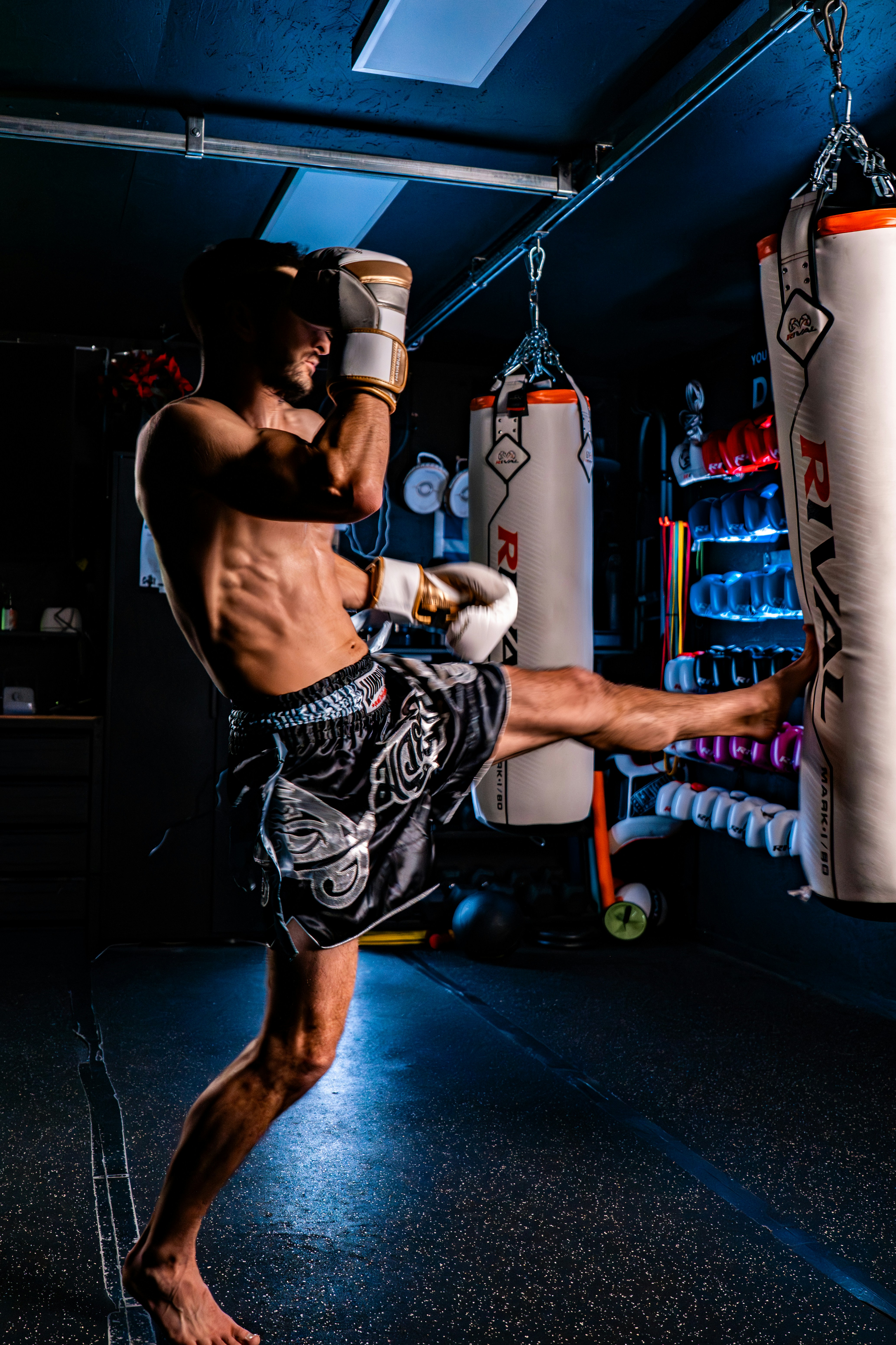 Man practicing muay thai kickboxing with a heavy bag.
