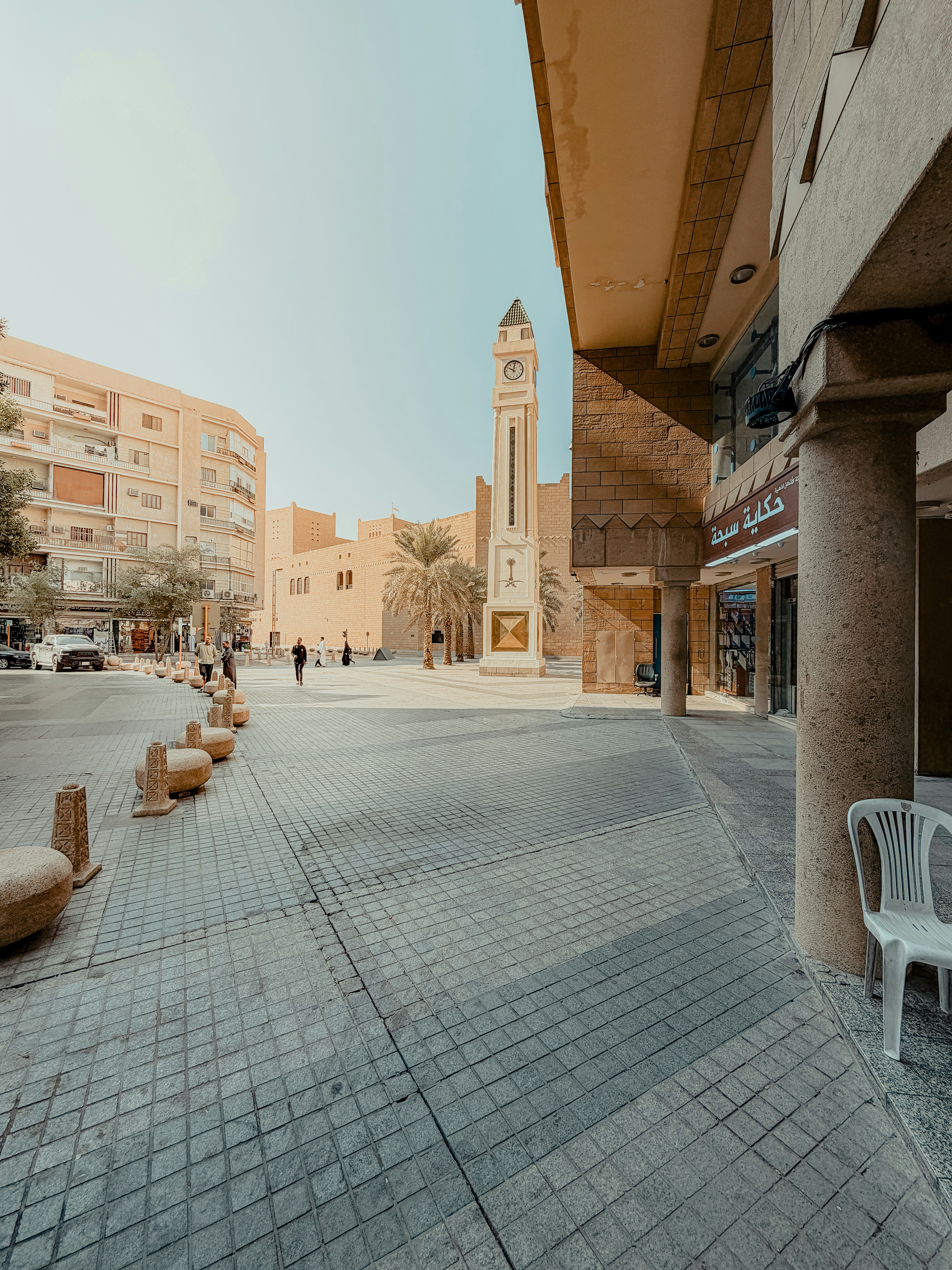 Uma torre do relógio está situada em uma praça ensolarada da cidade.