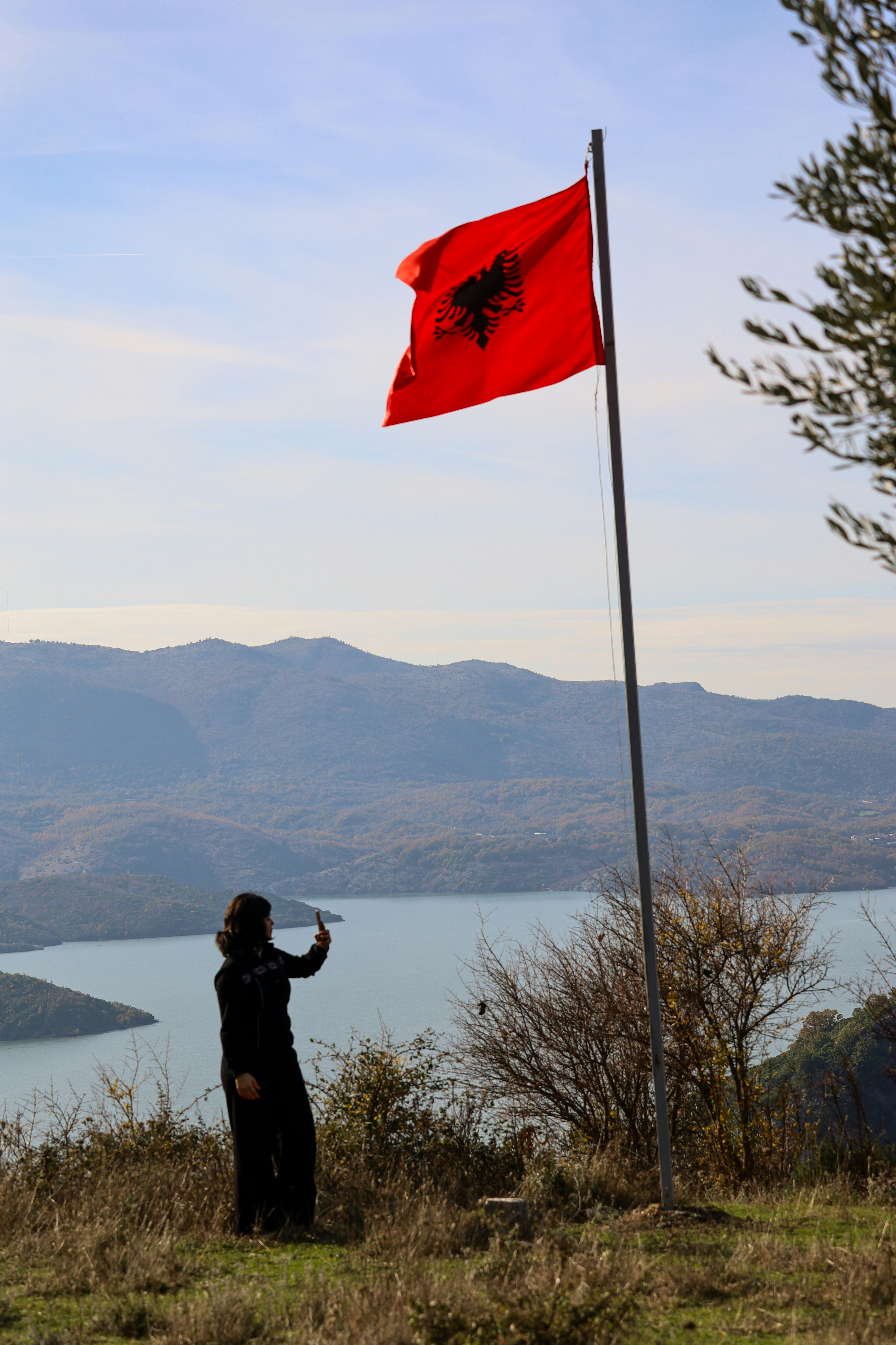 Femme avec un drapeau albanais surplombant un lac