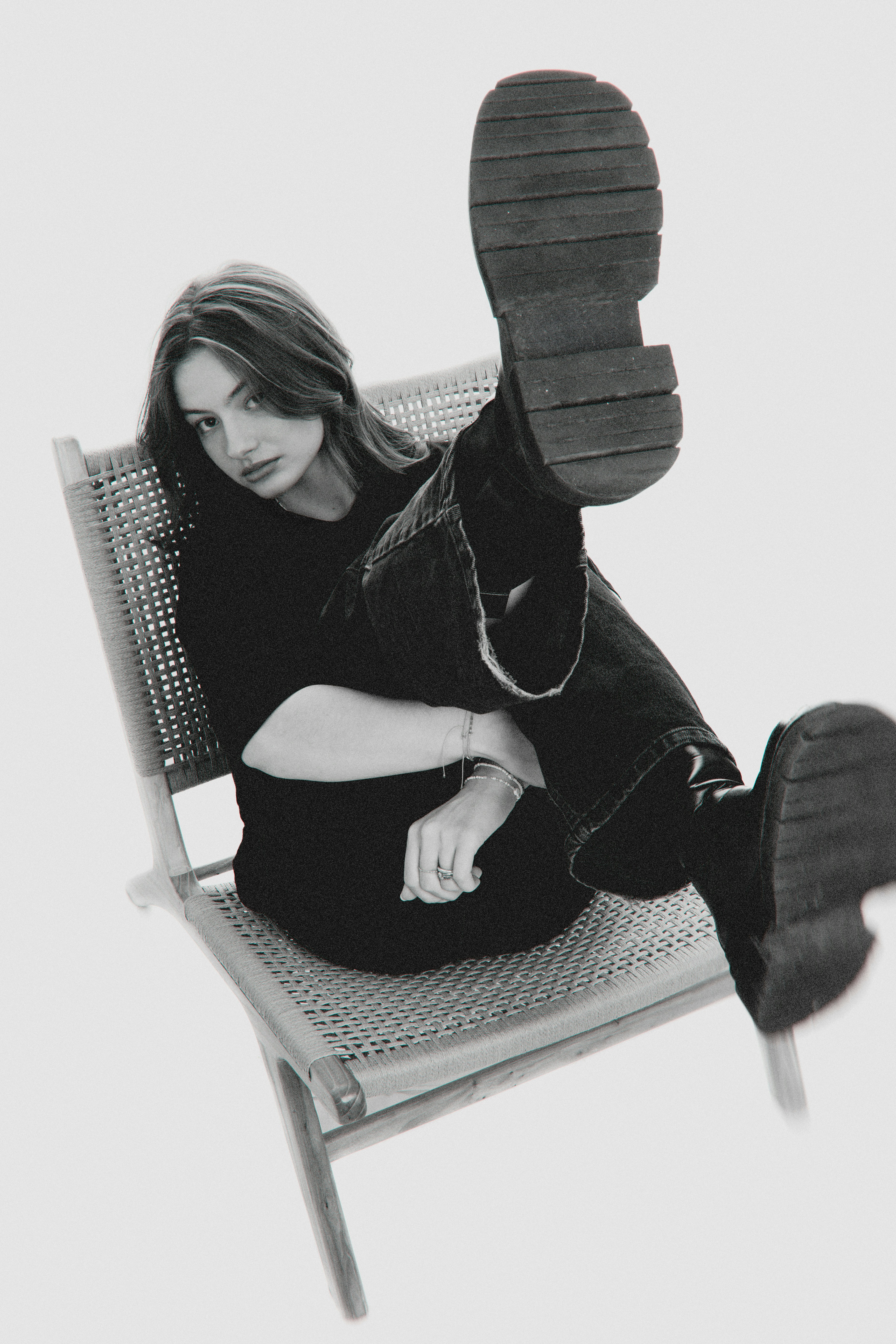 A woman sits on a chair with legs up.