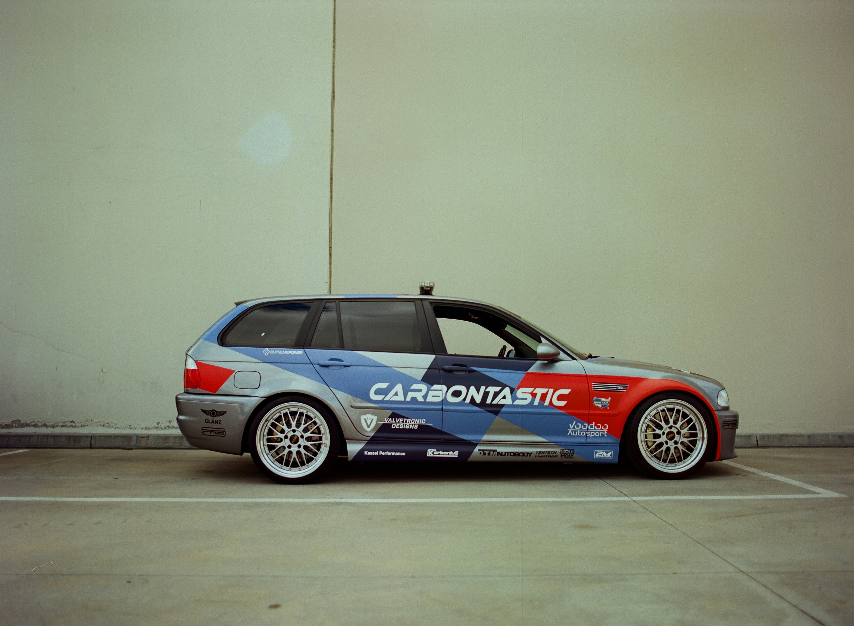 A racing station wagon parked against a wall