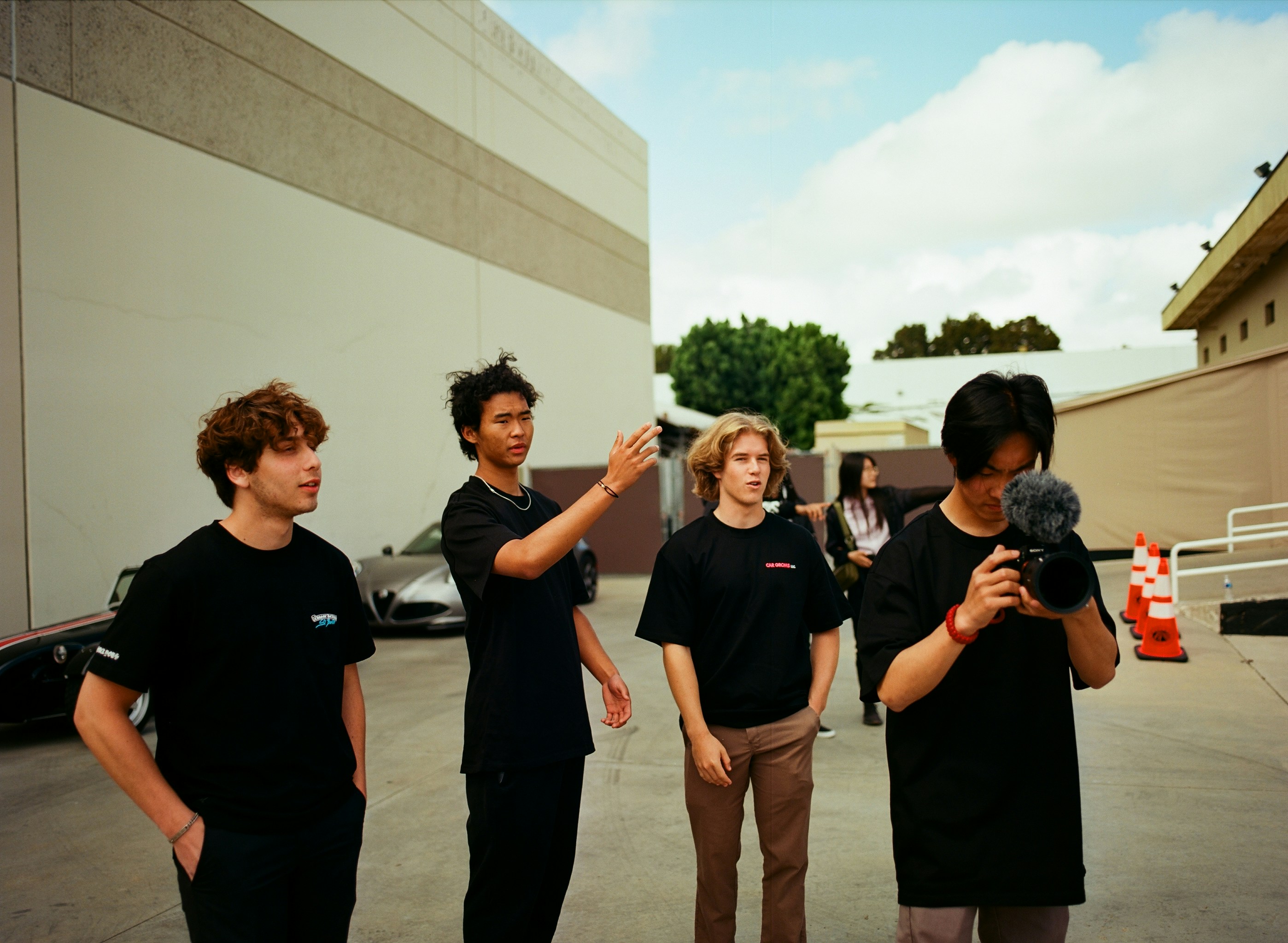 Four young men filming outdoors near buildings