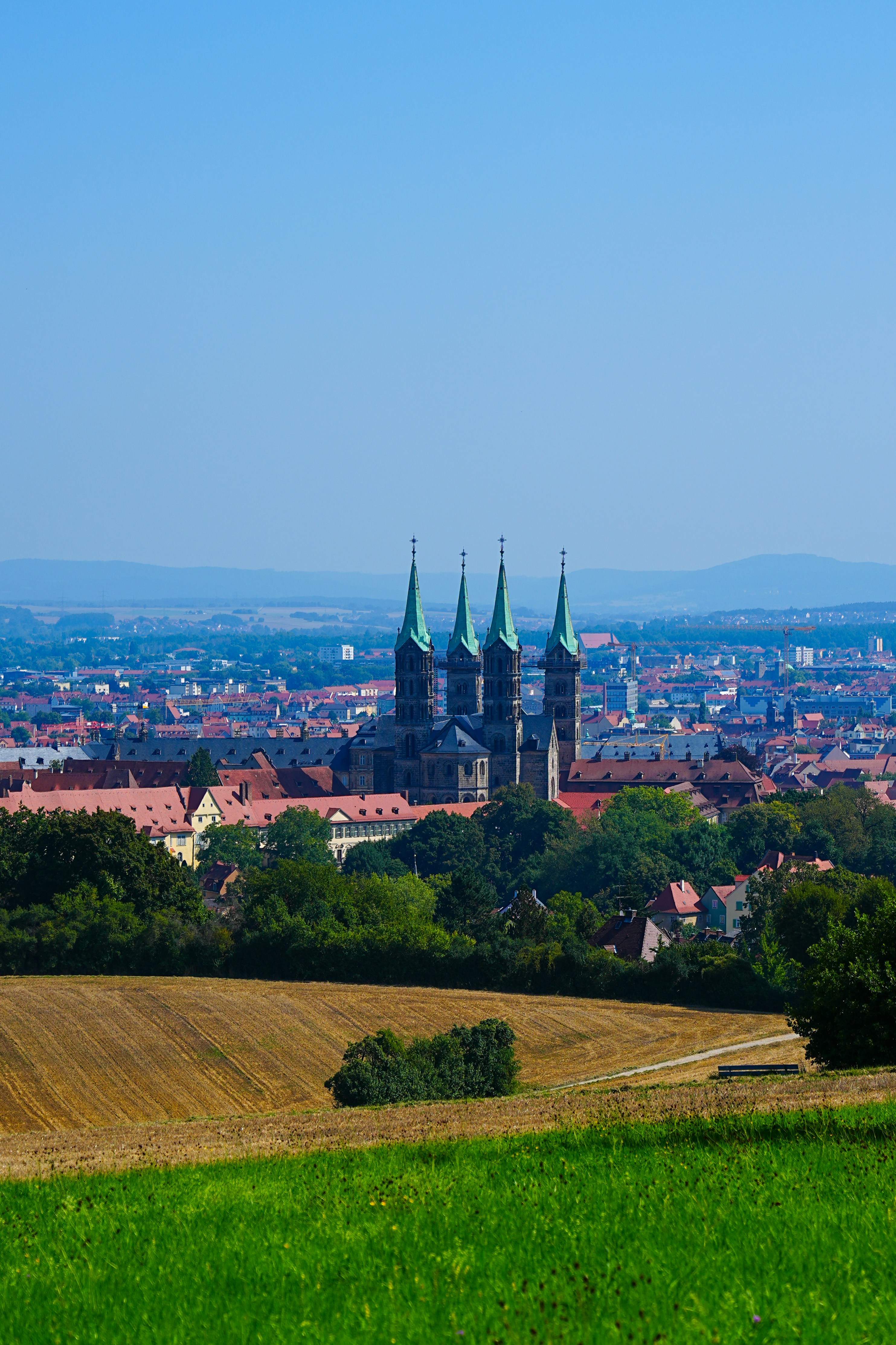 Cathedral with green spires overlooking a city.