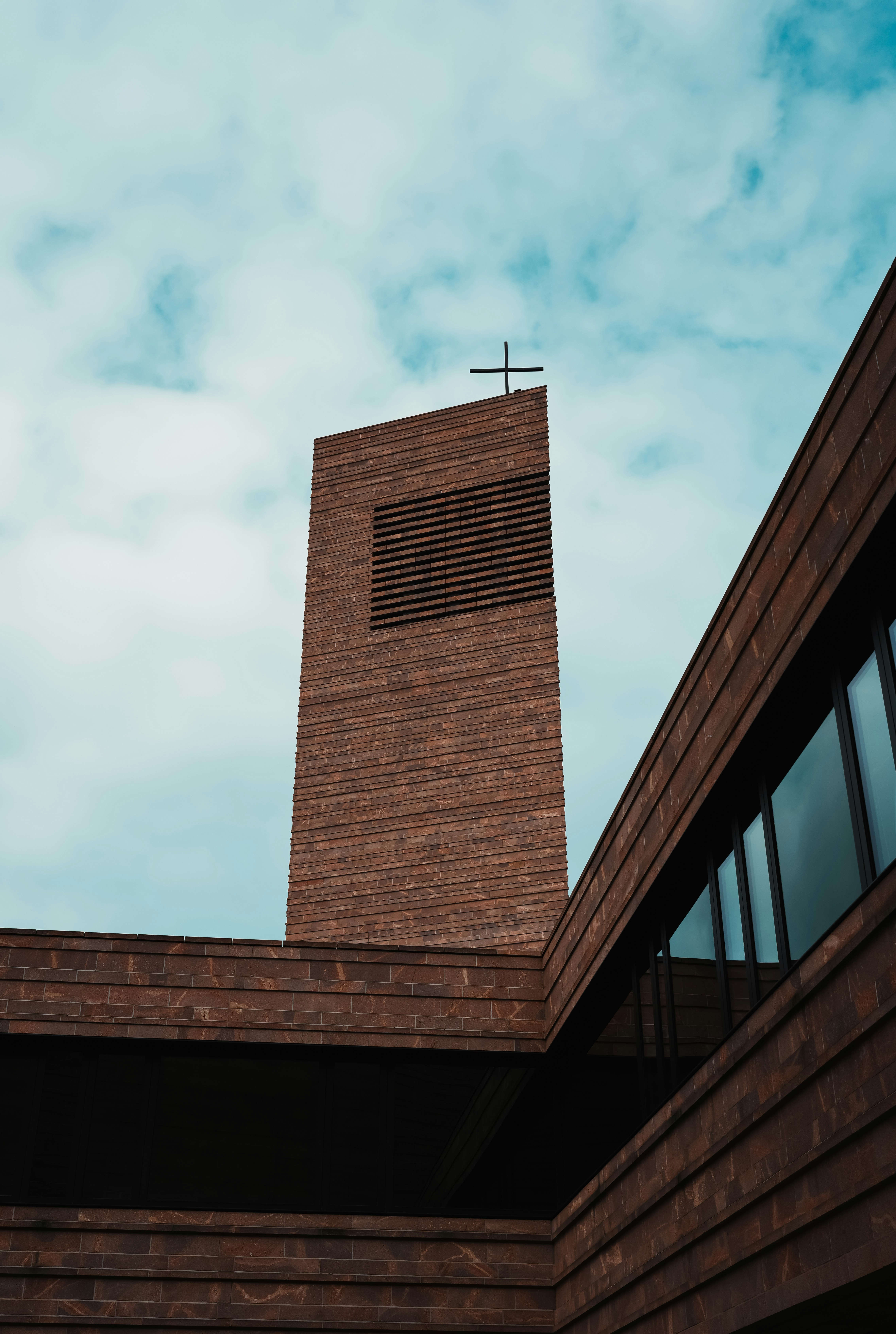 Modern brick church tower against a cloudy sky
