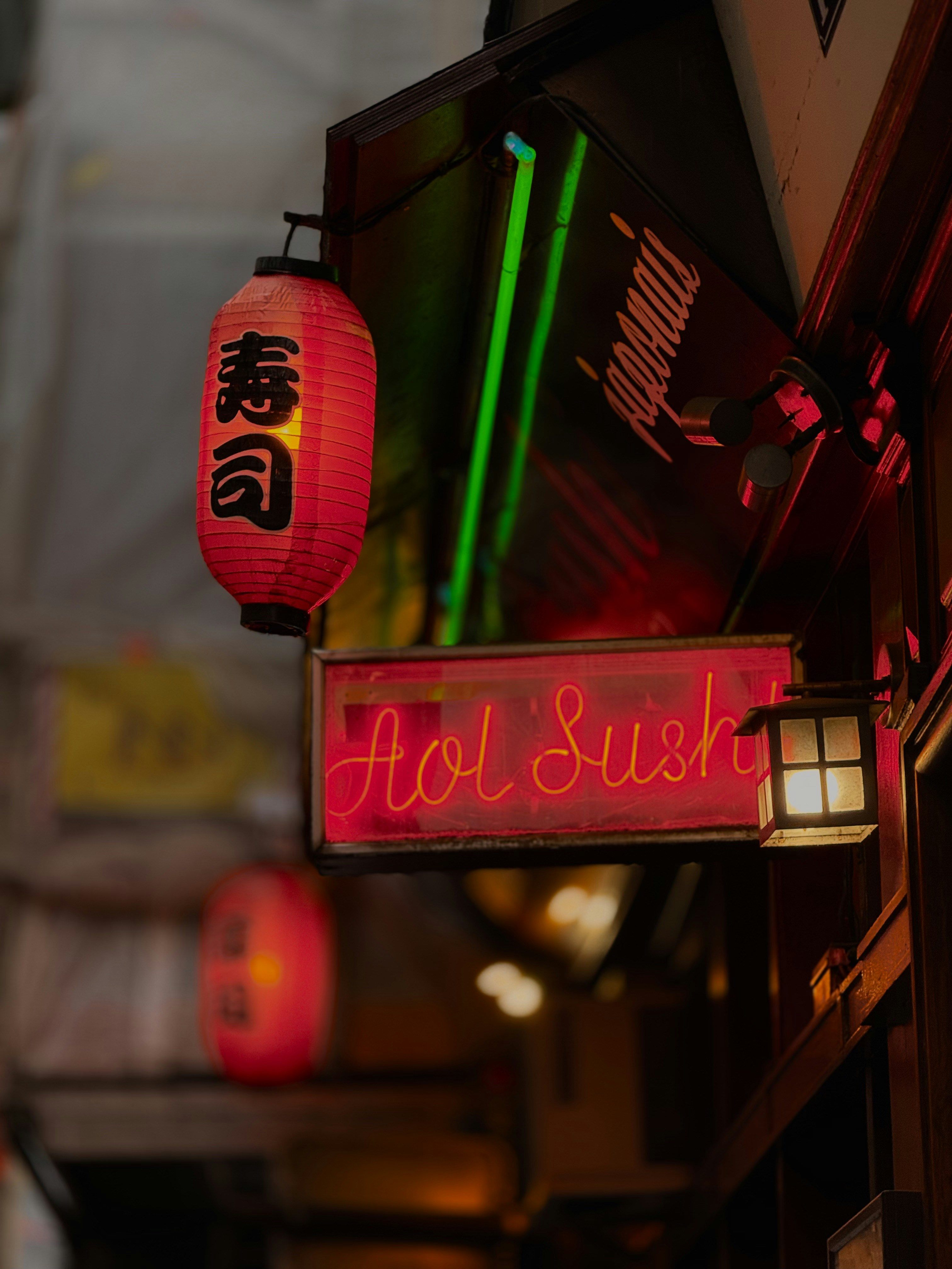 A red lantern and neon sign for aol sushi.