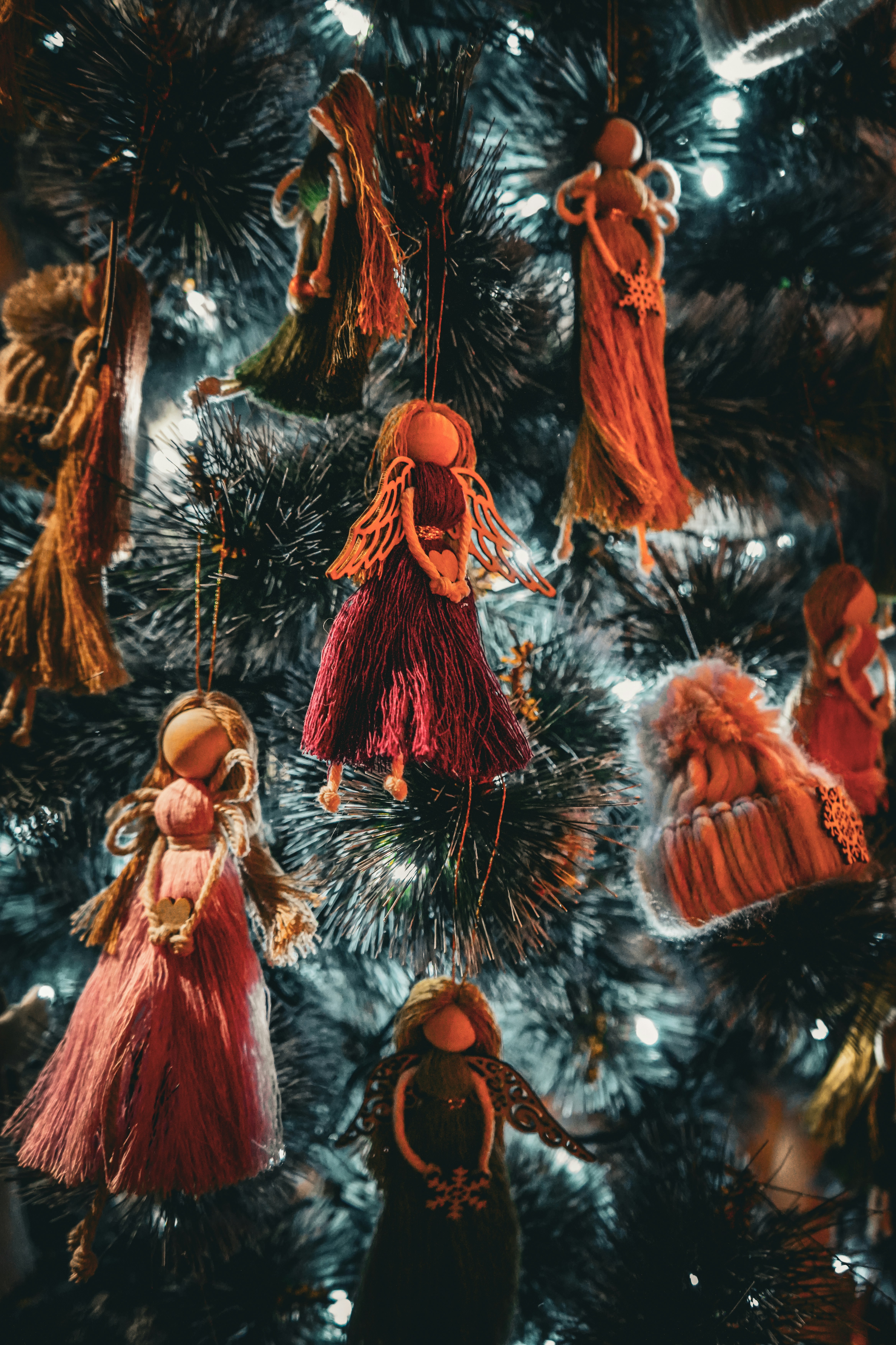 Handmade fabric dolls hang on a christmas tree.