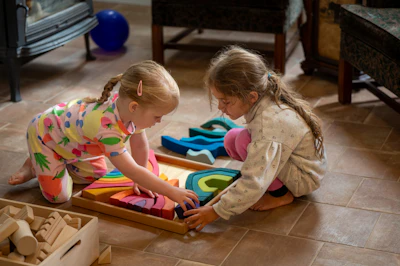 Two young girls playing with colorful wooden blocks.