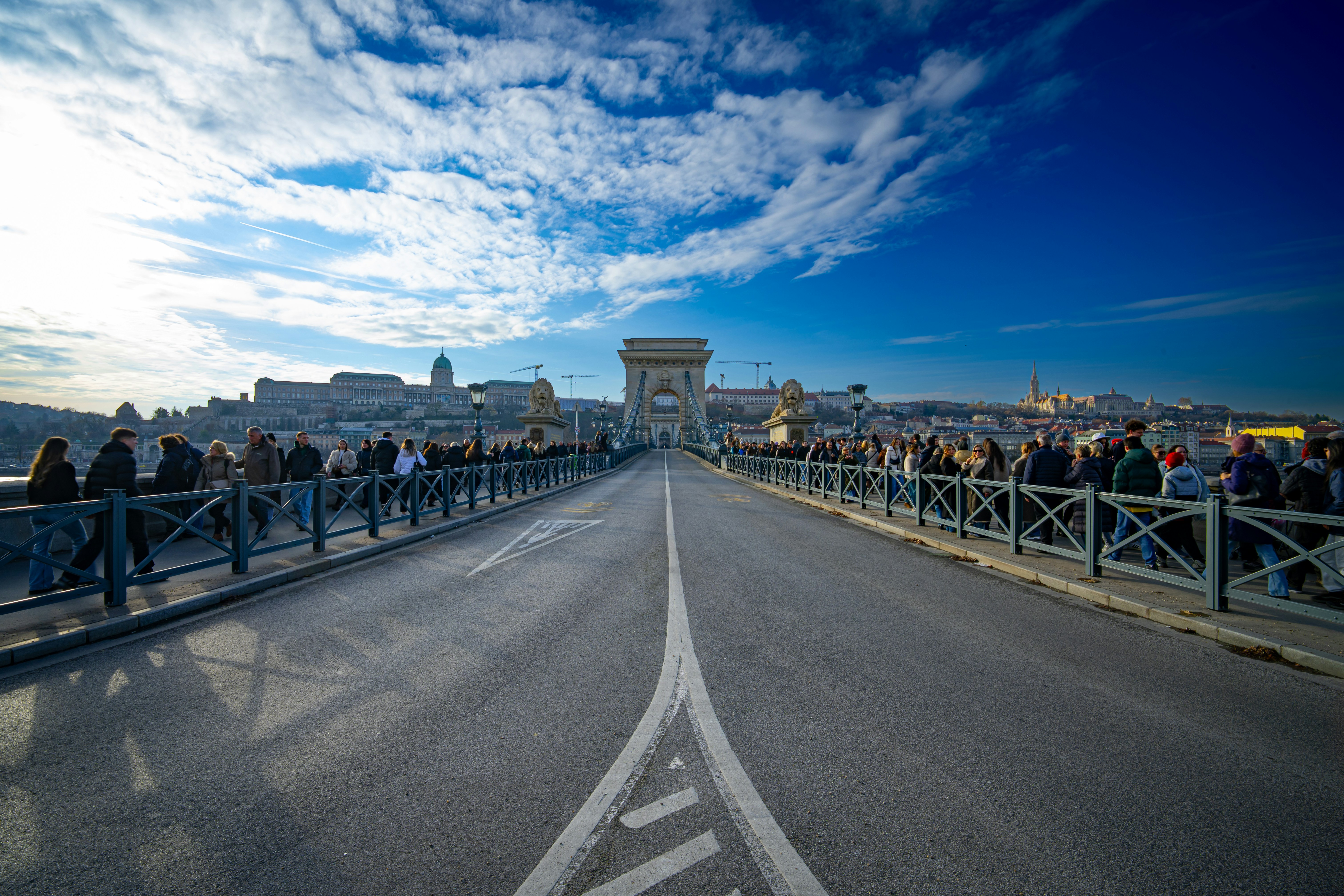 People walking on a bridge towards a city skyline.