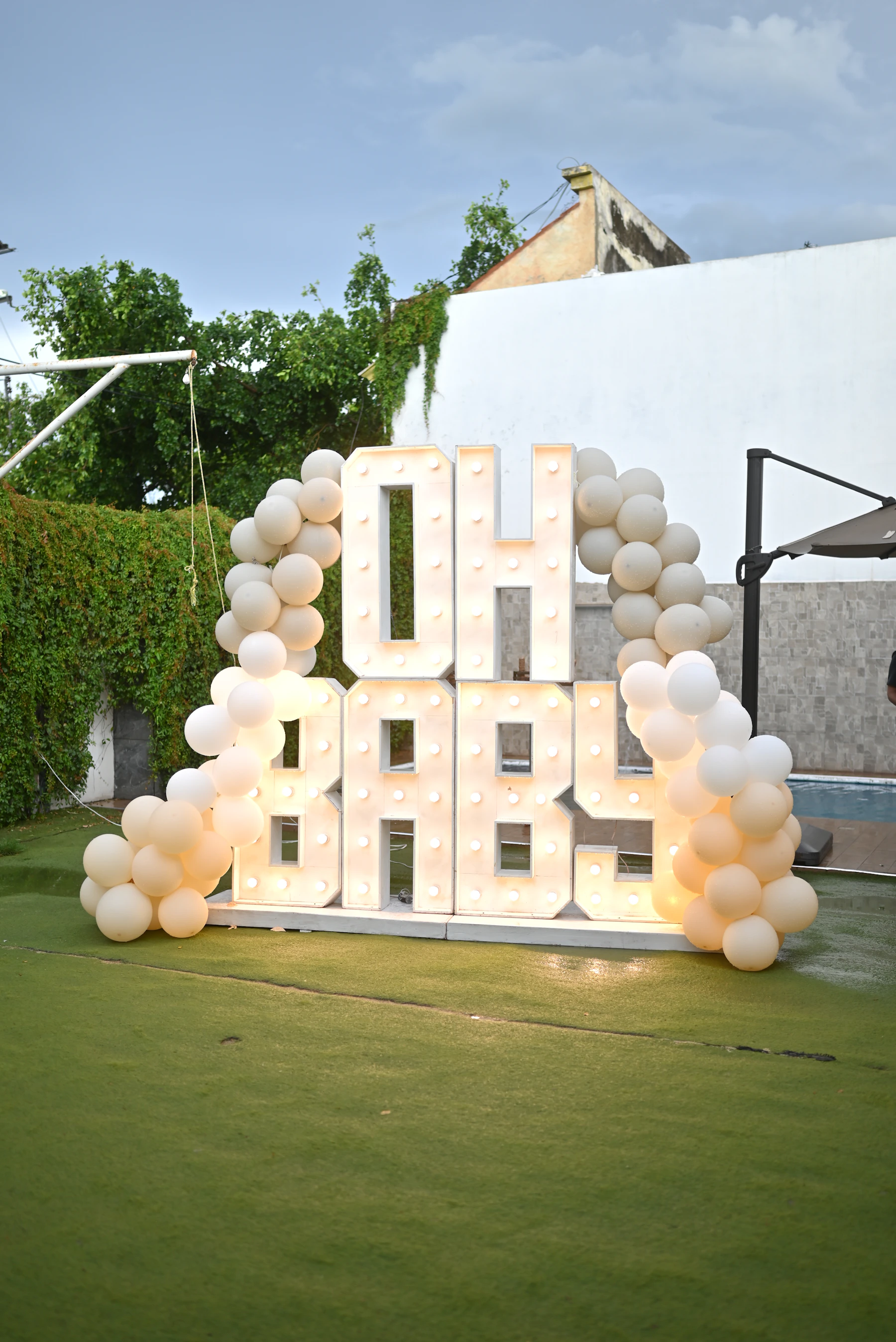 Baby shower celebration display with illuminated Oh Baby letters and balloon decorations