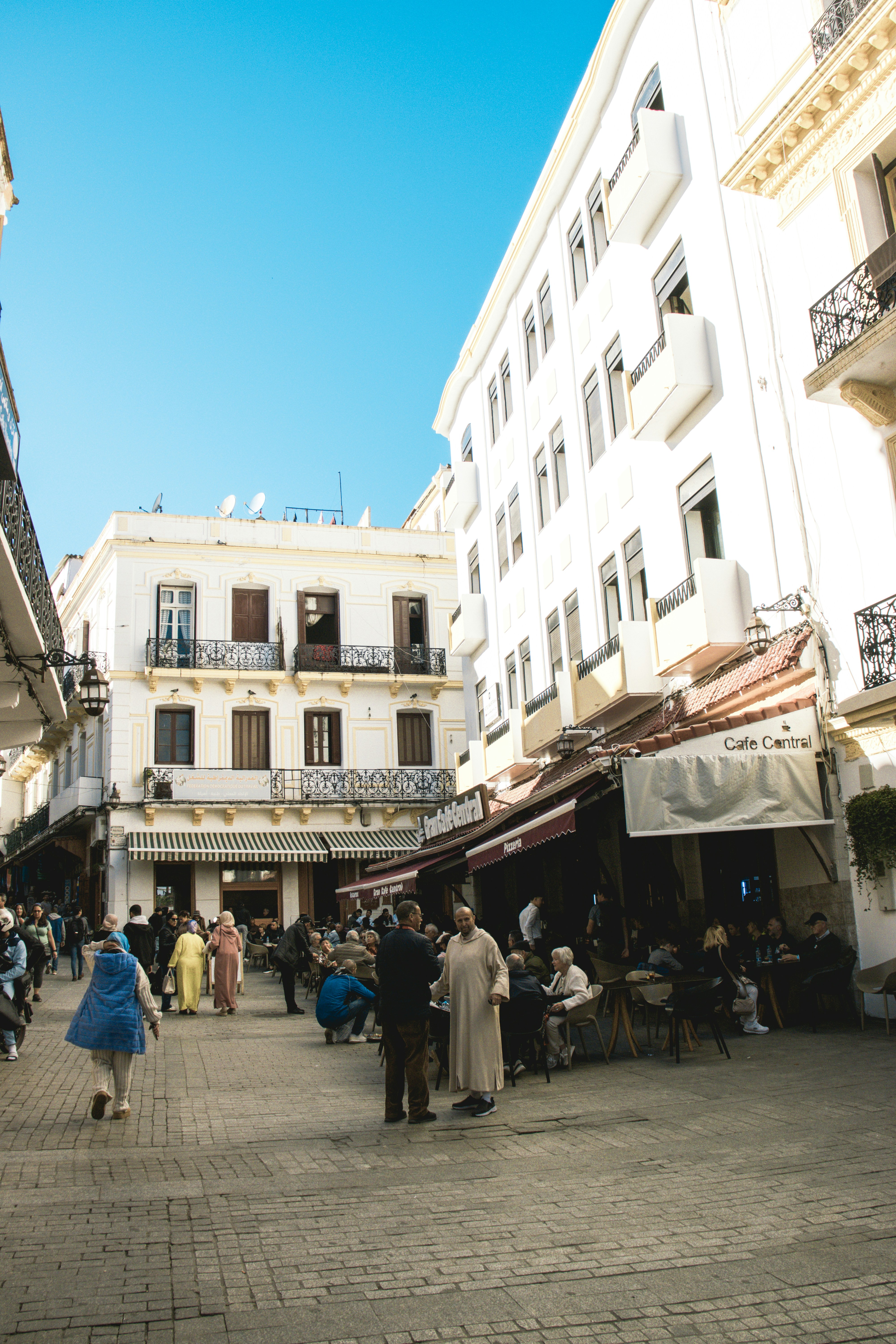 People walking on a cobblestone street in front of buildings.