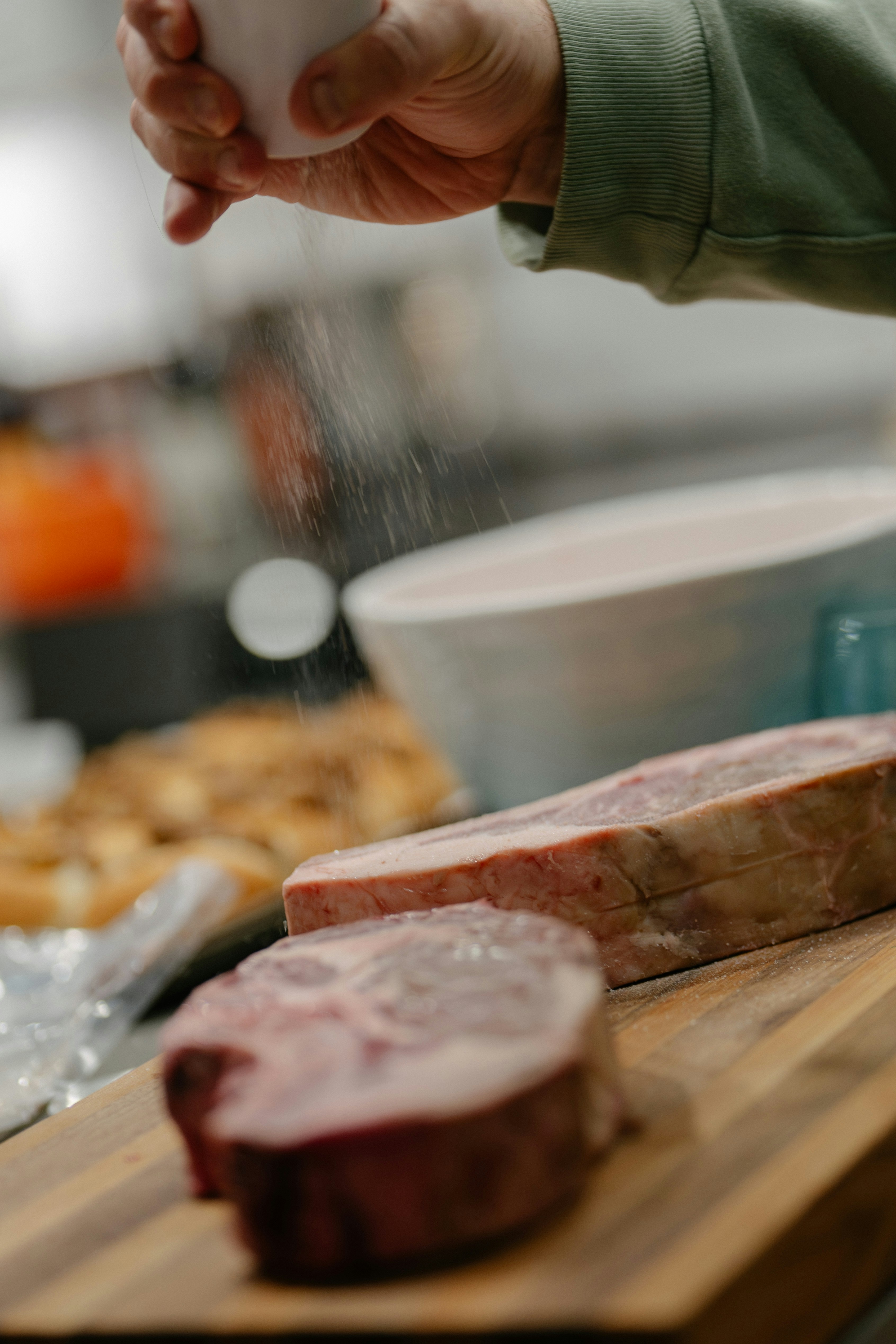Someone seasoning raw meat with salt