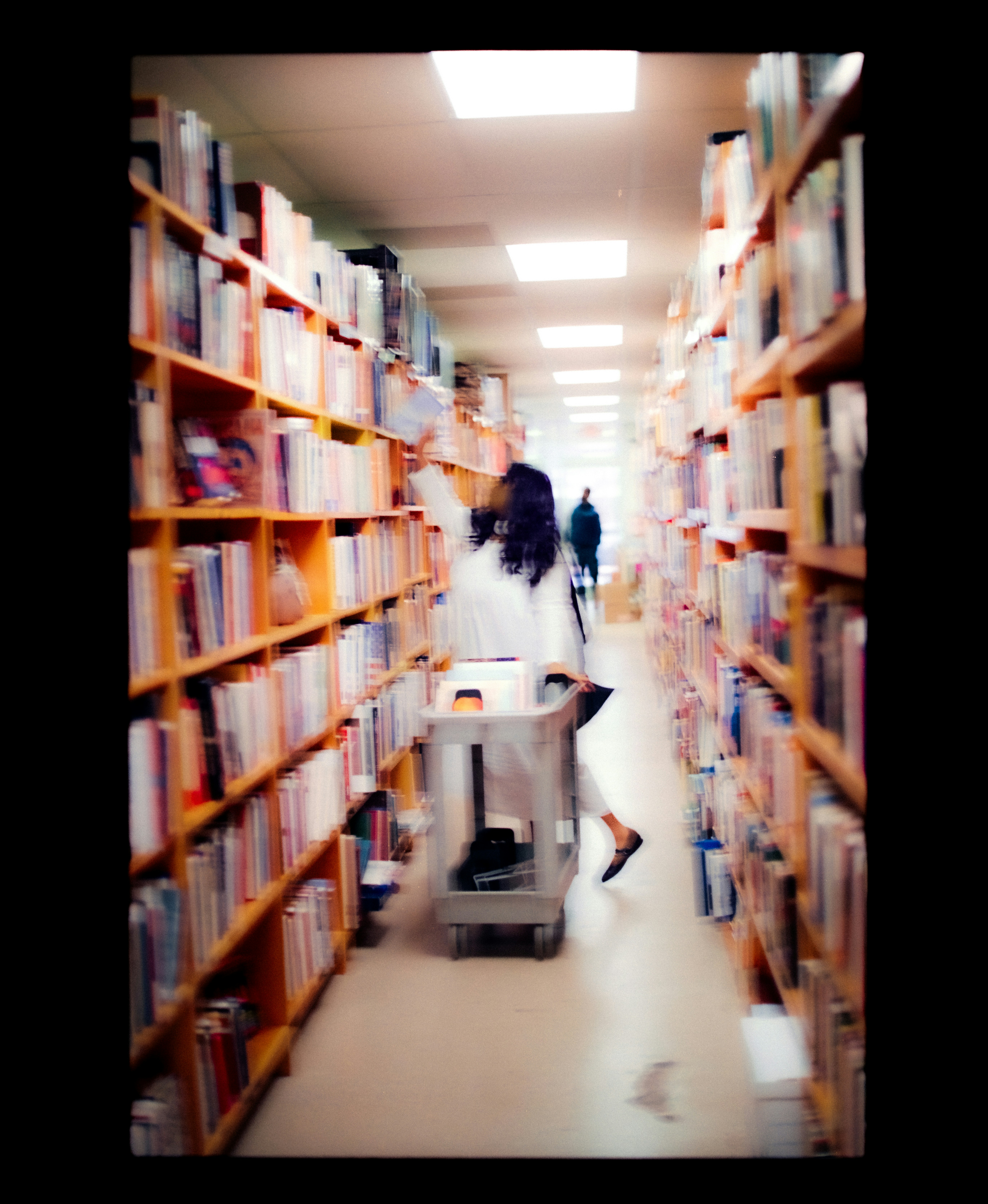 Person reaching for book in library aisle