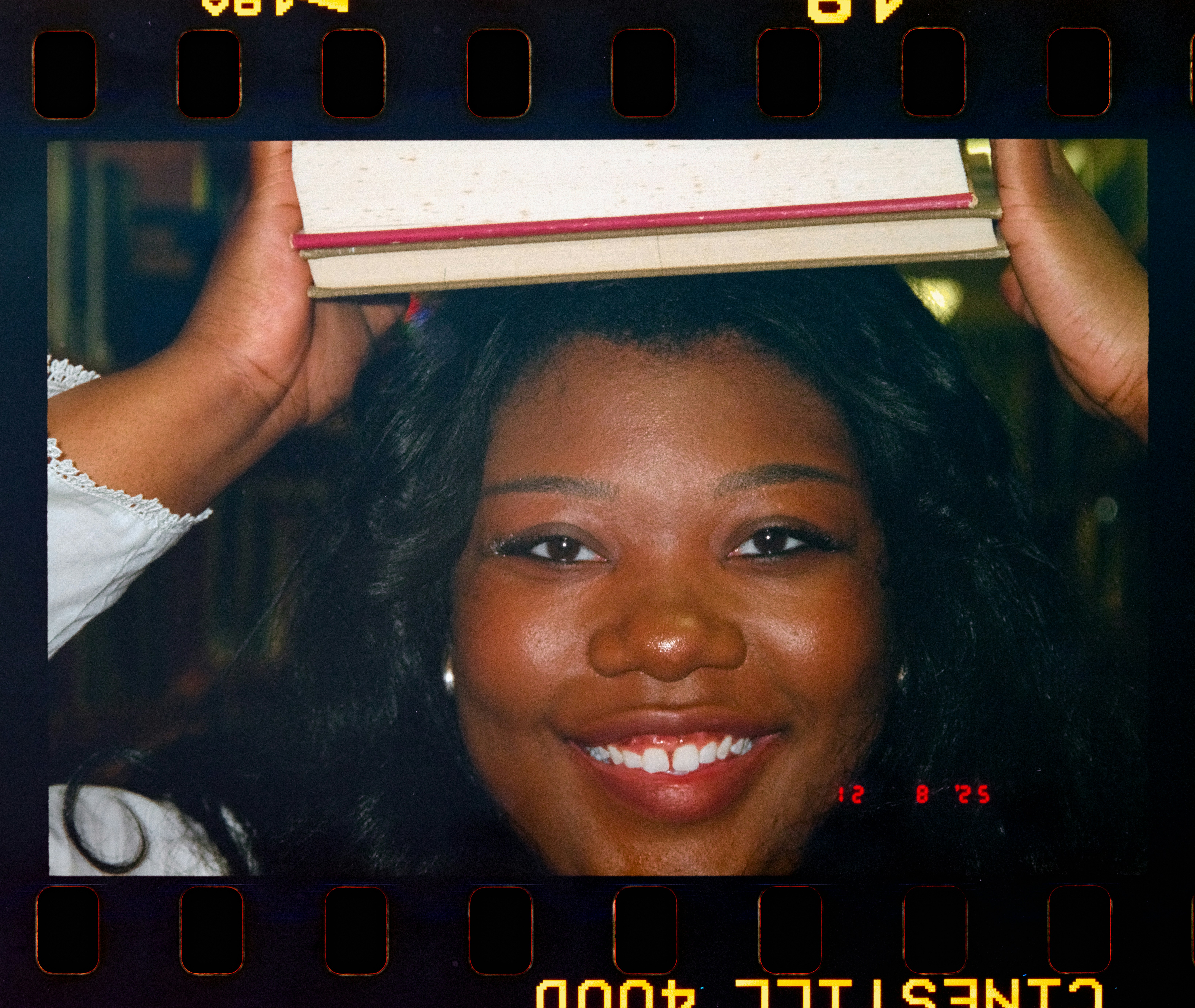 Young woman smiling with book on head