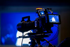 Professional video camera on tripod with blue background