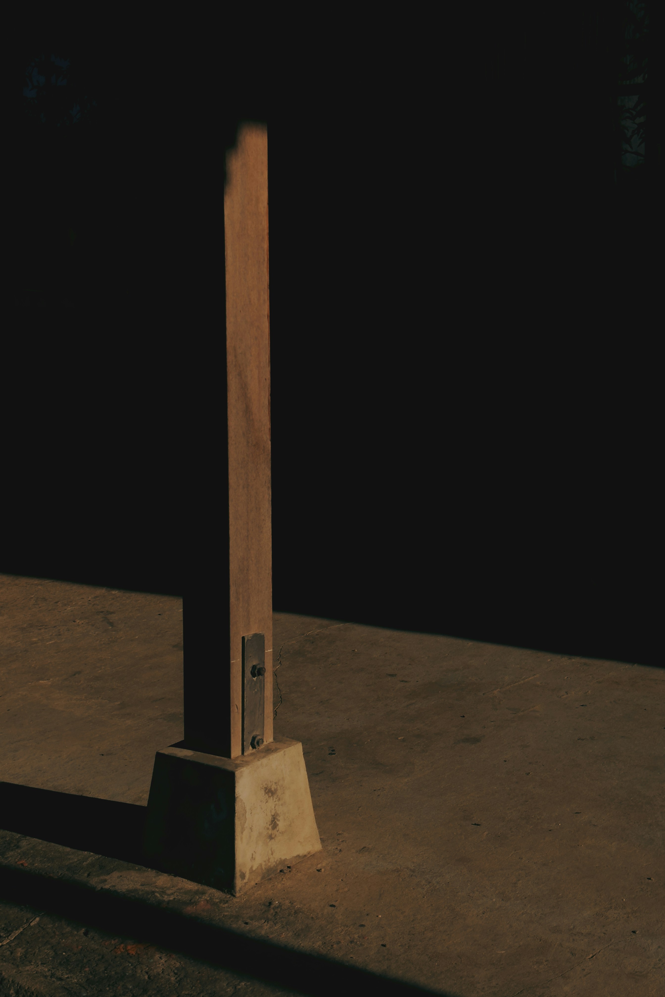 Wooden post with concrete base in sunlight