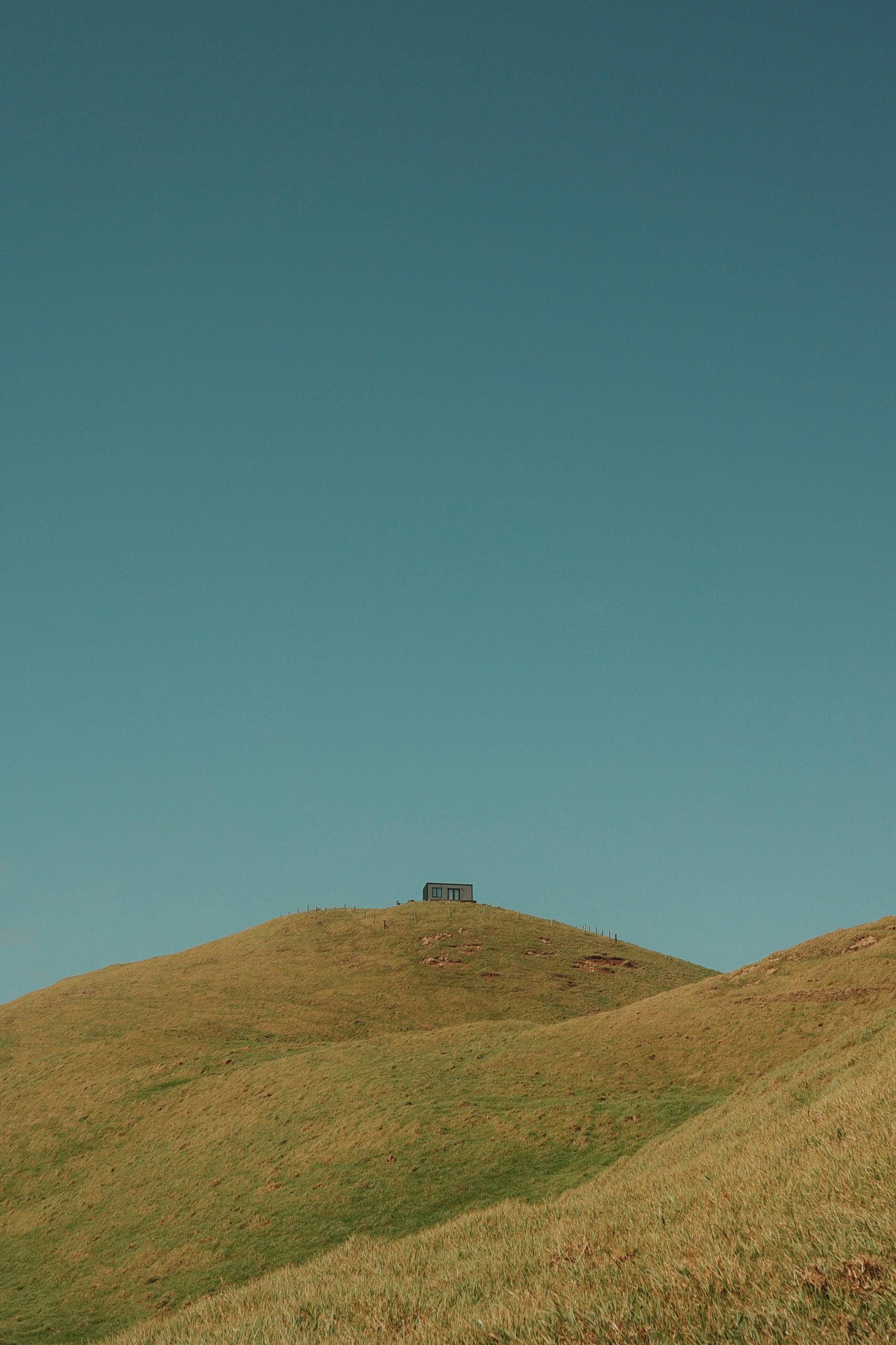 A small building sits atop a grassy hill.