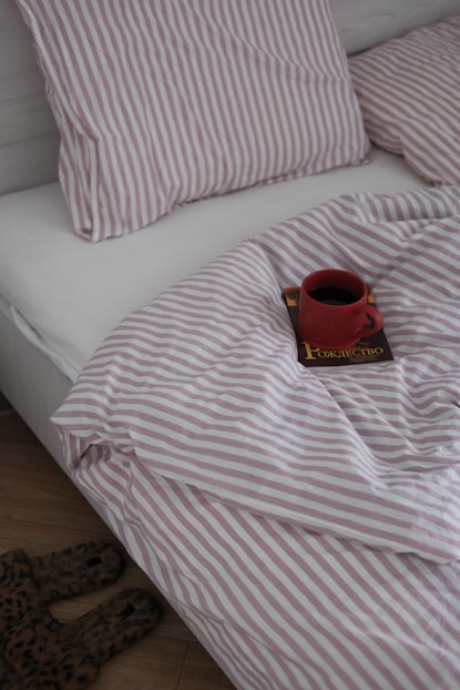 Red mug of coffee on a book in bed