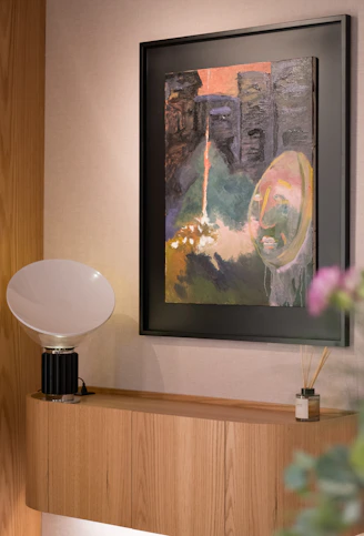 Framed abstract painting hangs above a modern shelf