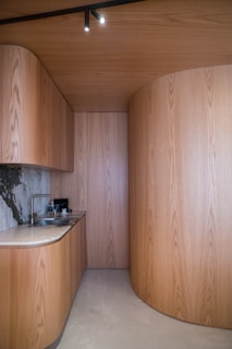 Modern kitchen with curved wooden walls and countertop.