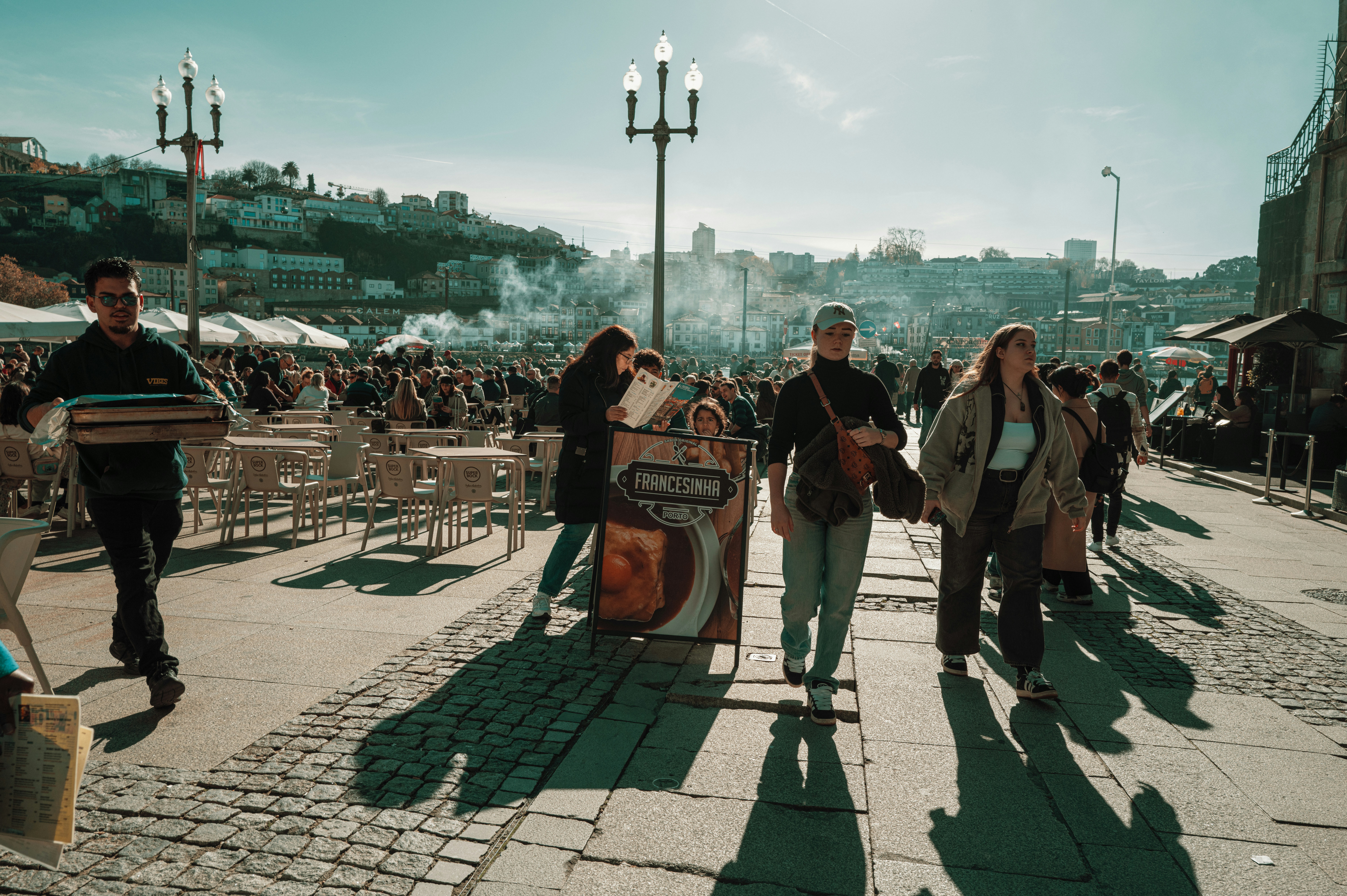 Des gens se promenant sur une place de marché ensoleillée en plein air.