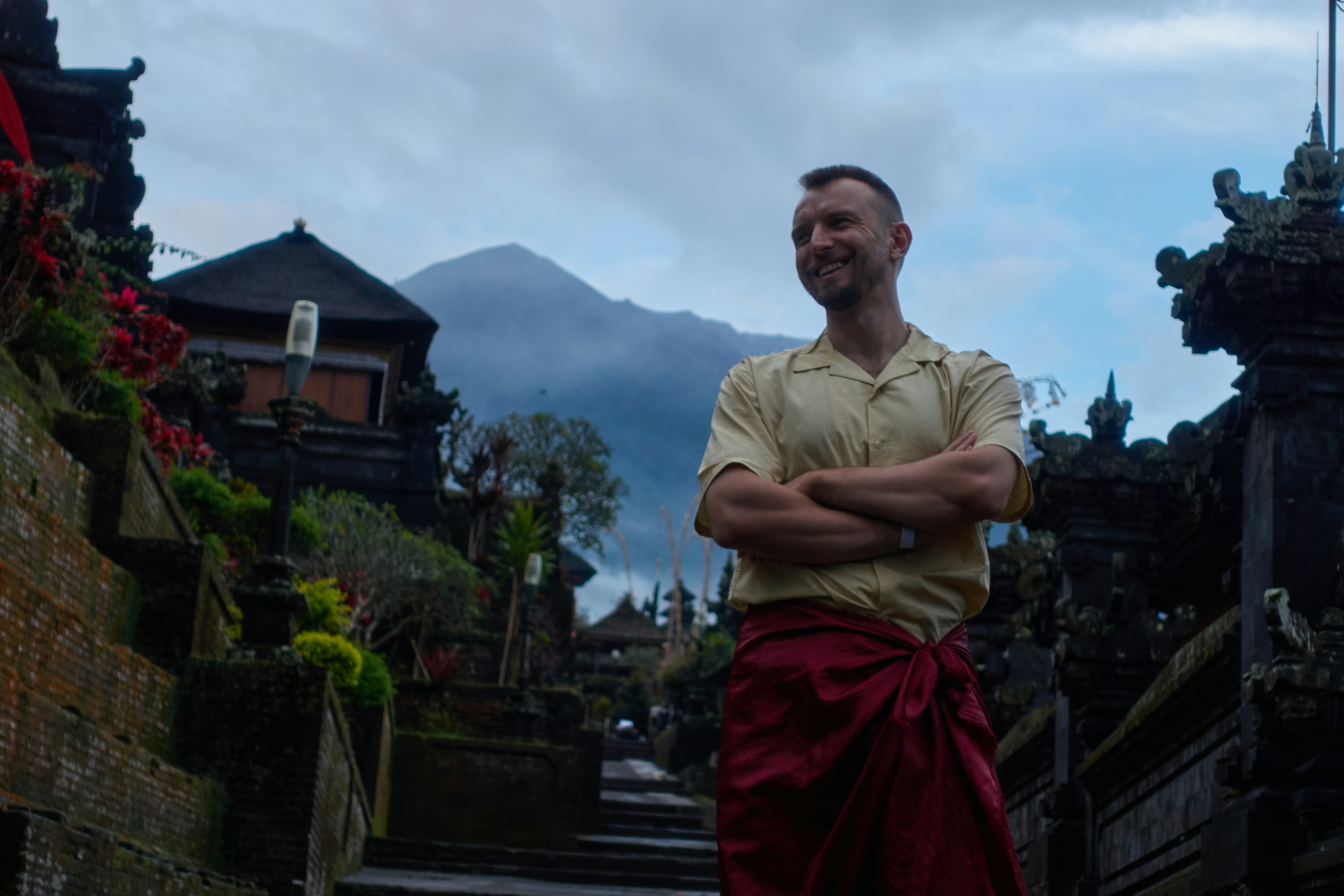 Man in traditional attire at ancient temple with mountain