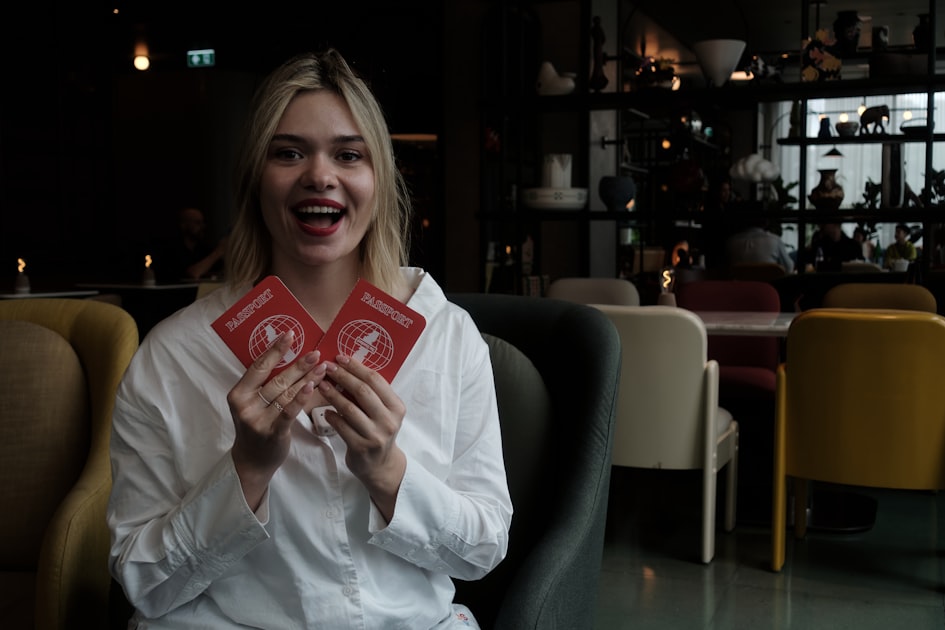 Young woman holds two red passports smiling faces cards
